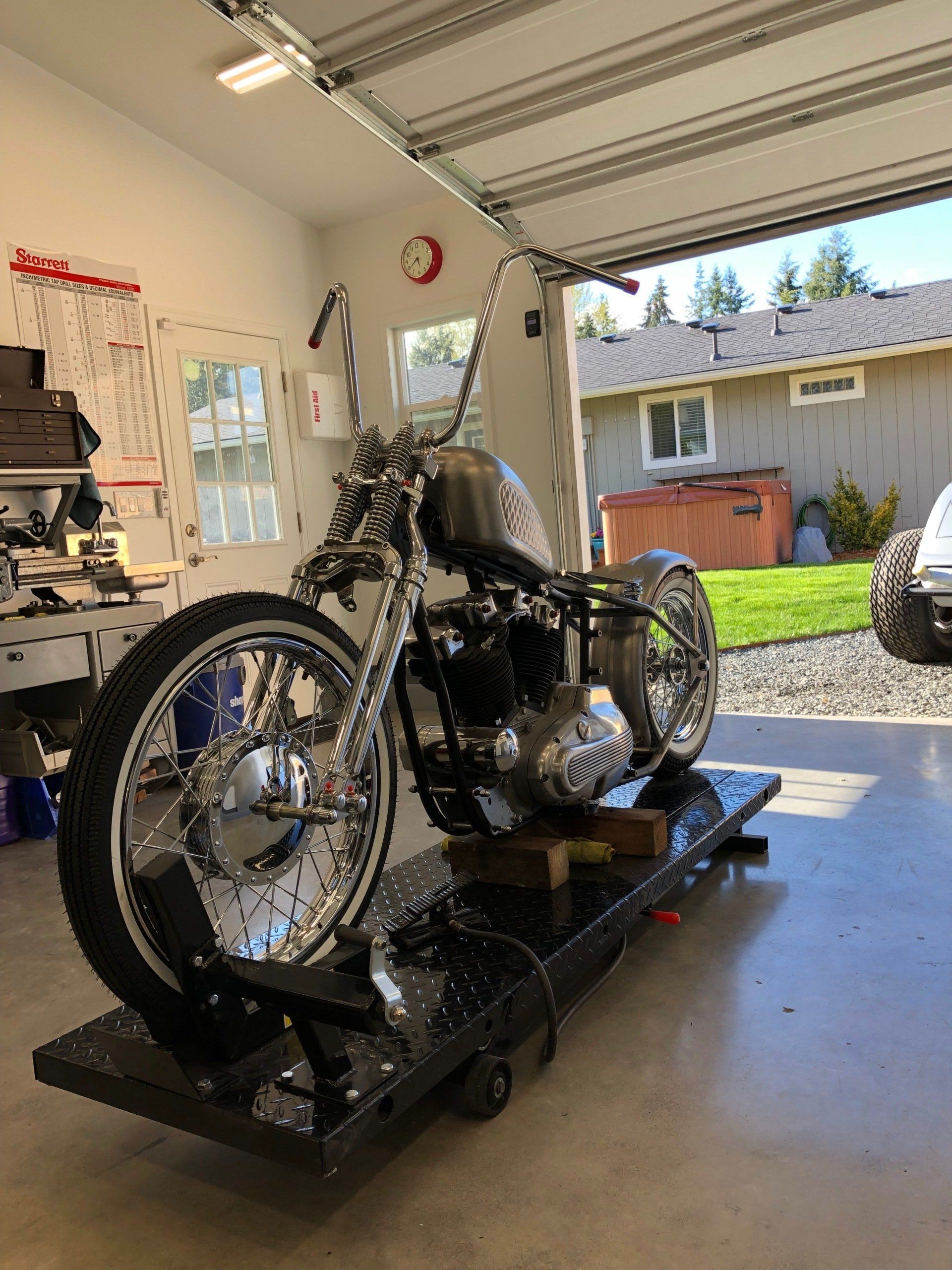 A motorcycle is parked in a garage with the garage door open.