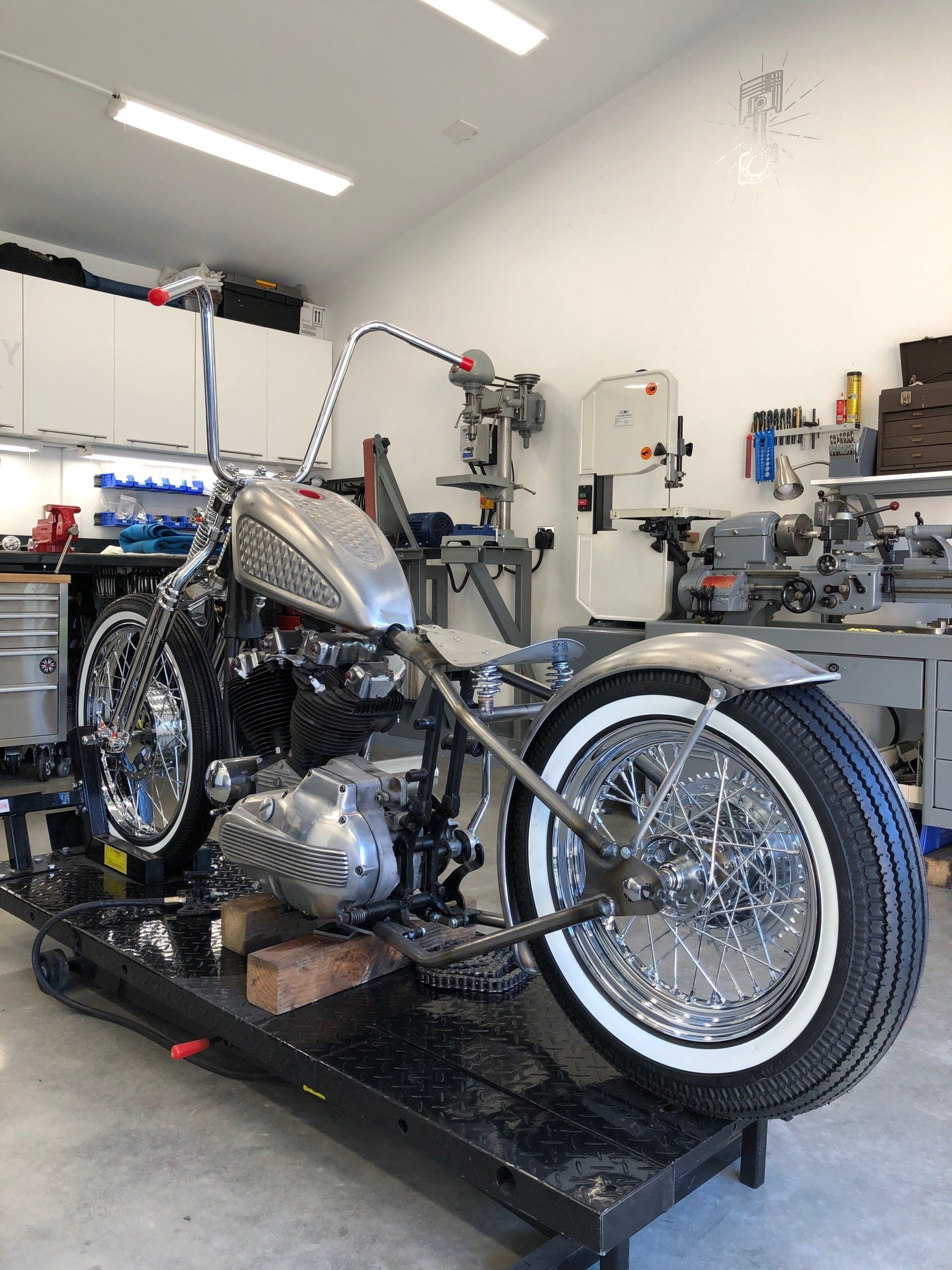 A motorcycle is sitting on a lift in a garage.