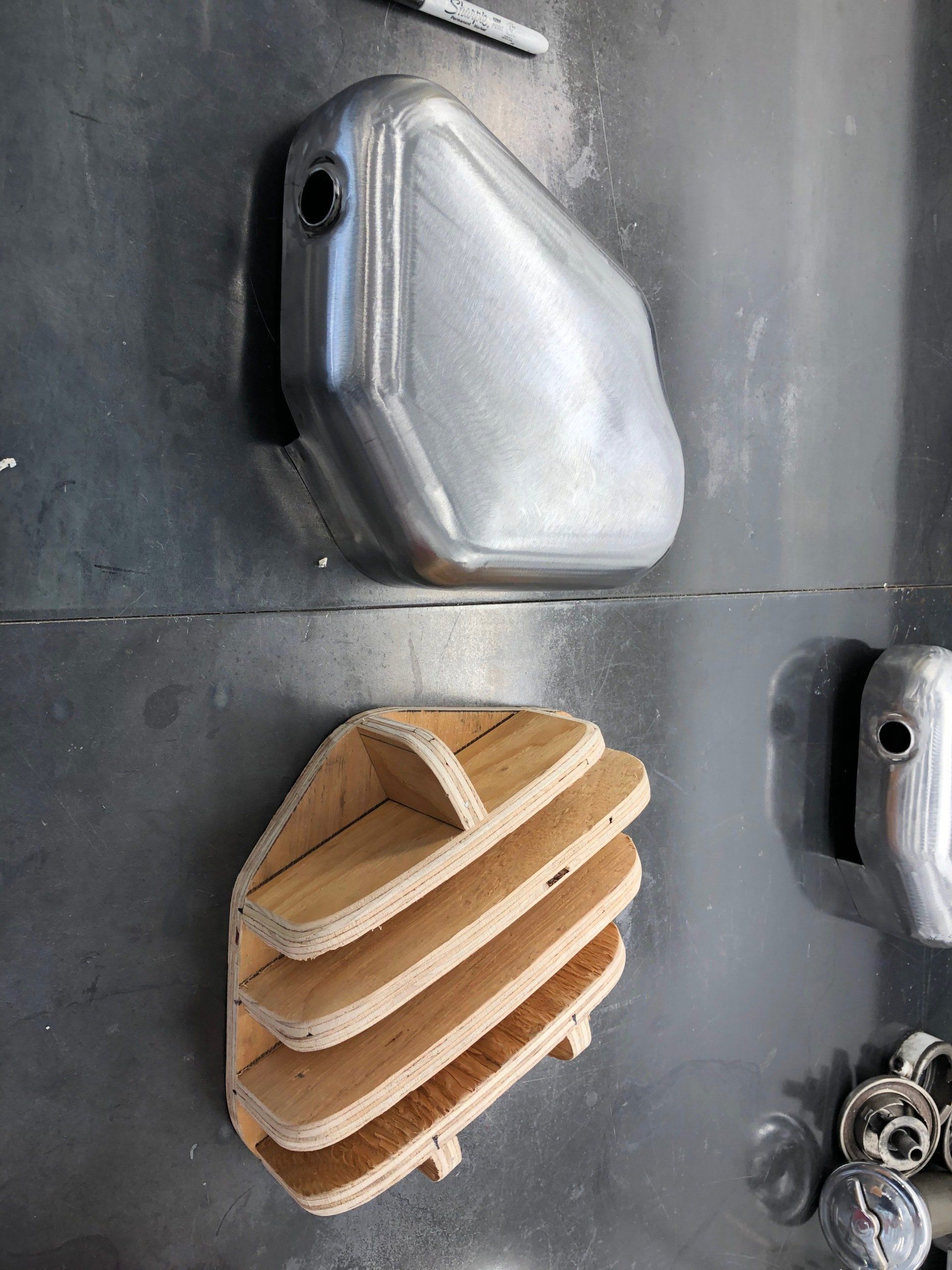 A metal tank and a wooden shelf are sitting on a metal surface.