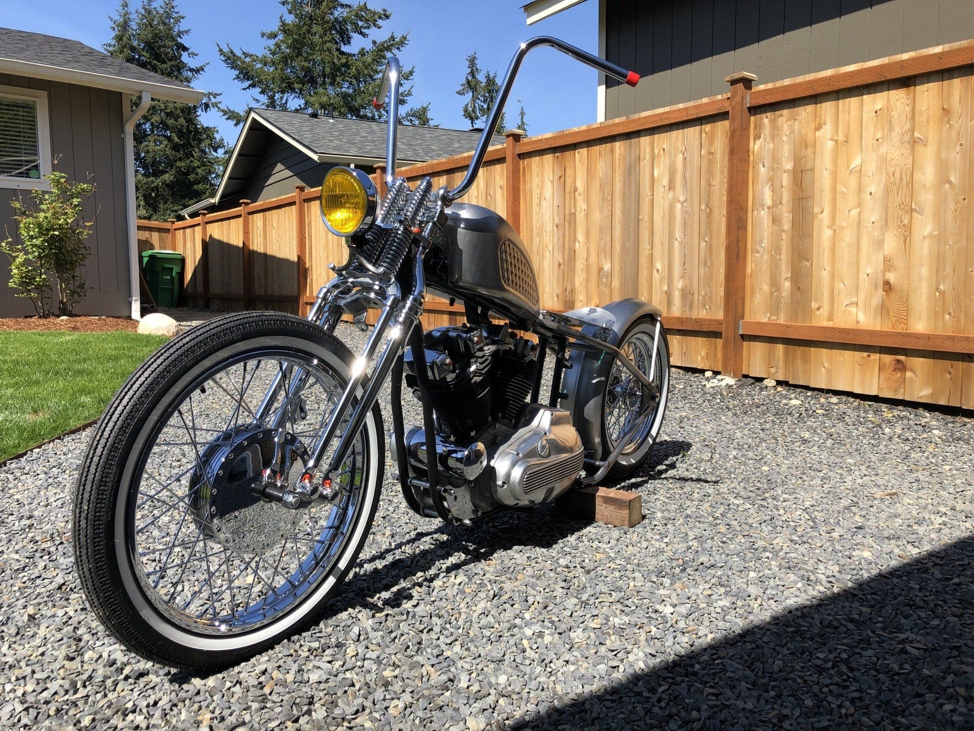 A motorcycle is parked in front of a wooden fence.