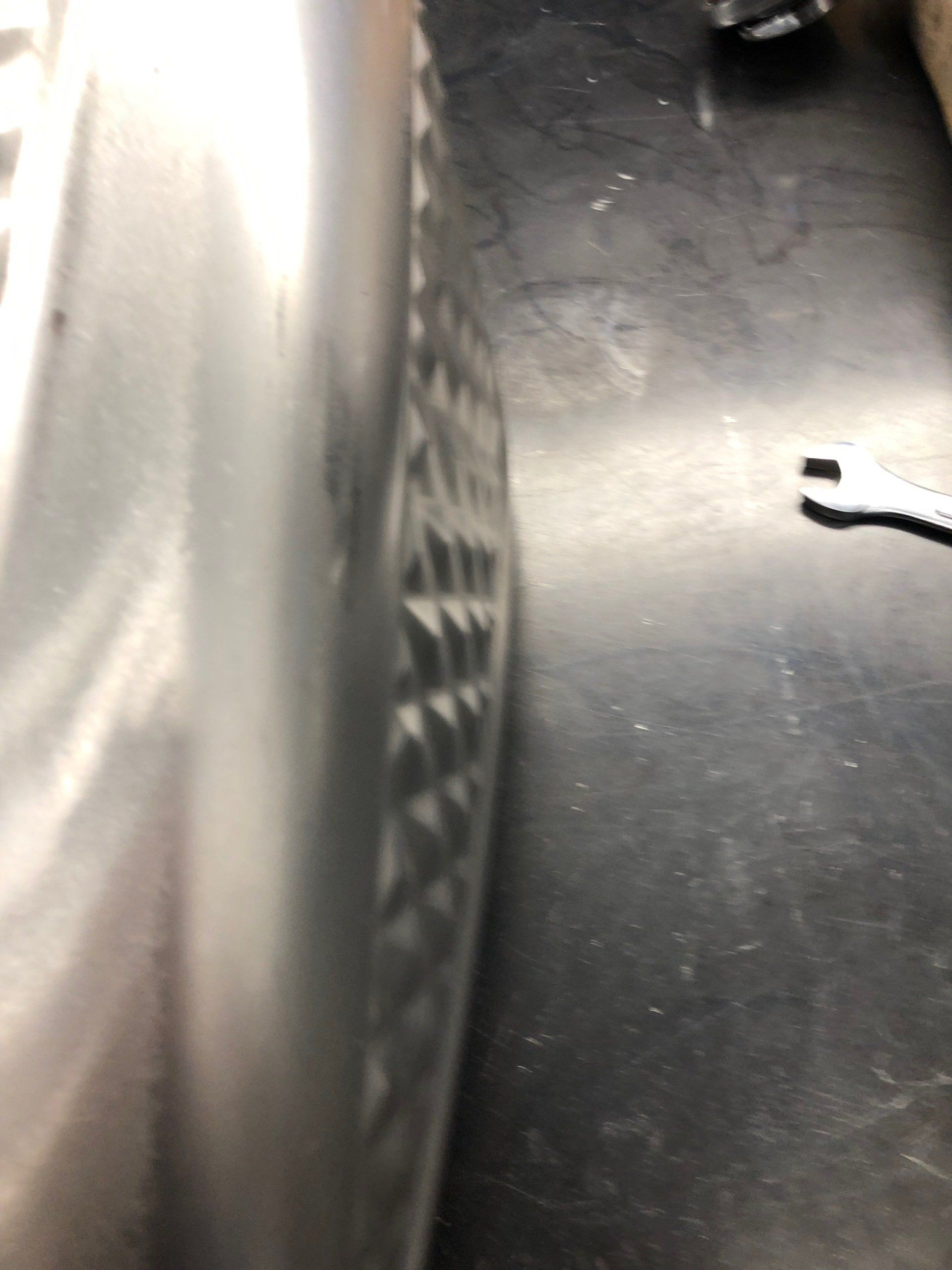 A close up of a tire on a black surface next to a wrench.