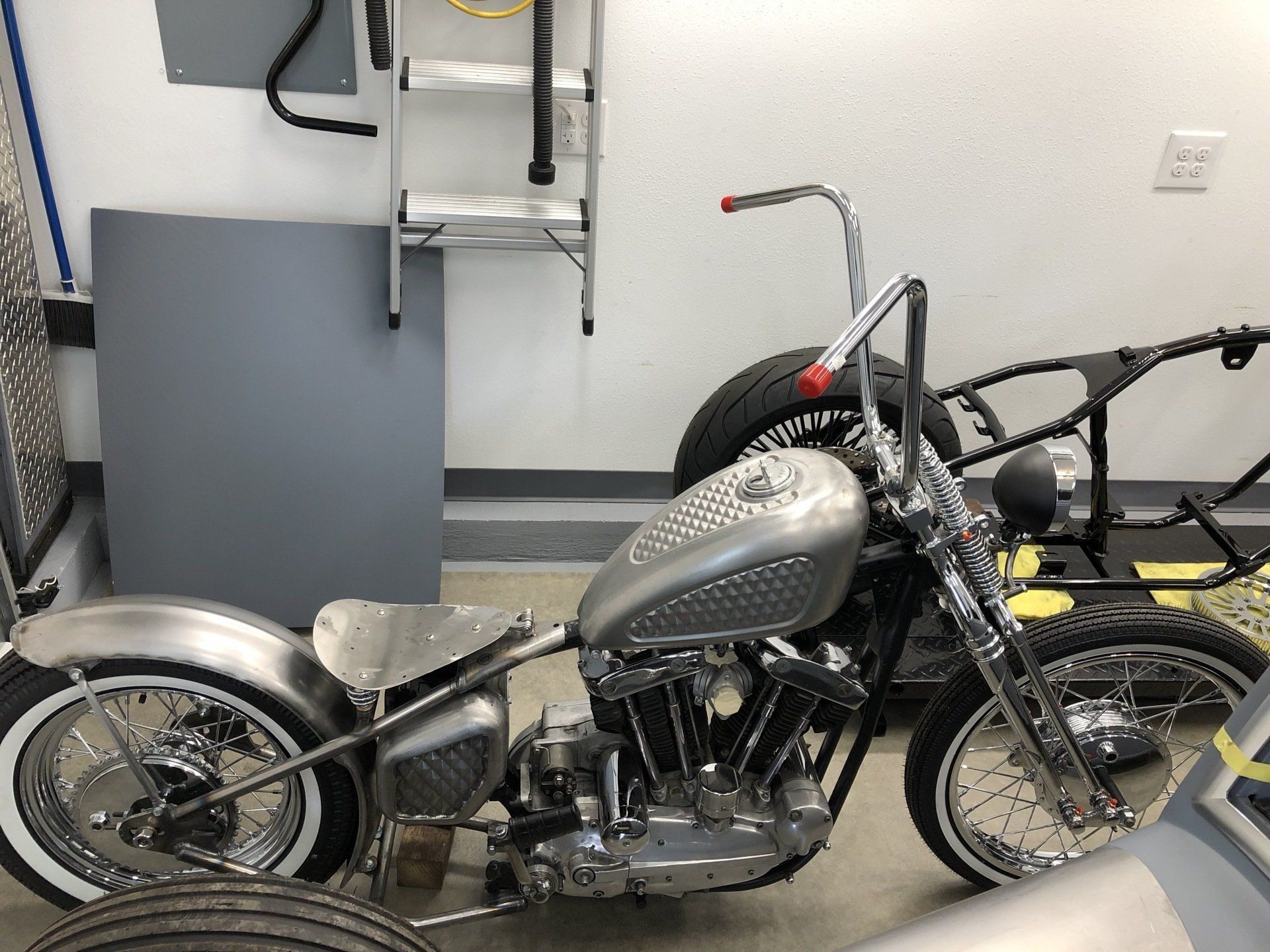 A motorcycle is parked in a garage next to a ladder.