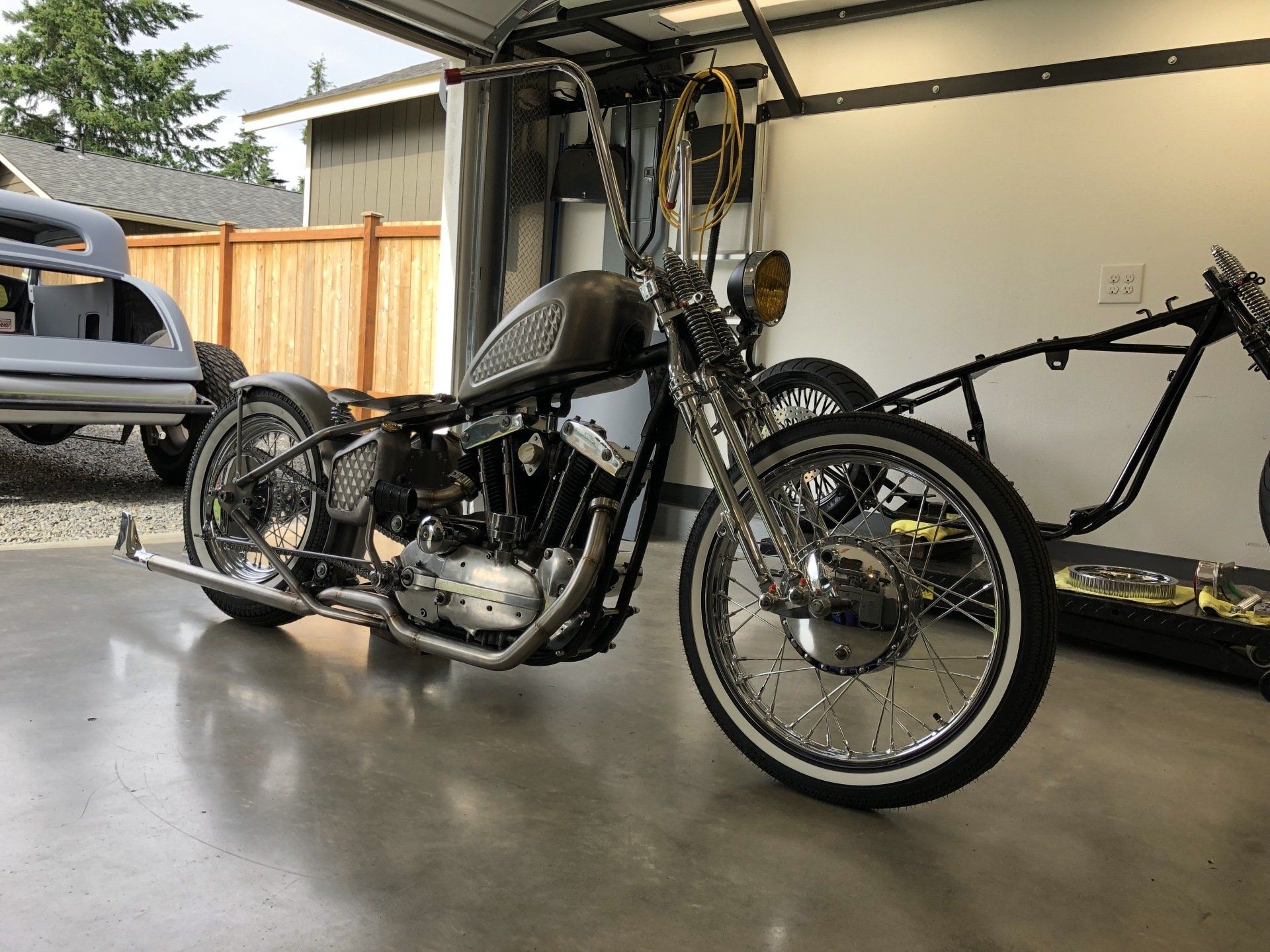 A motorcycle is parked in a garage next to a trailer.