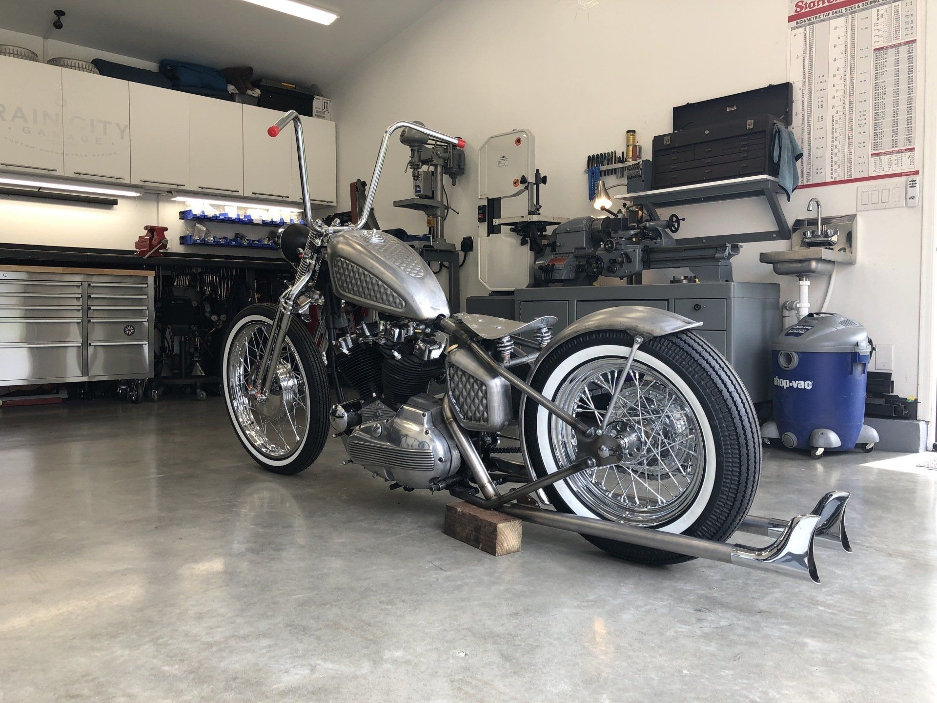 A motorcycle is parked in a garage with white tires.