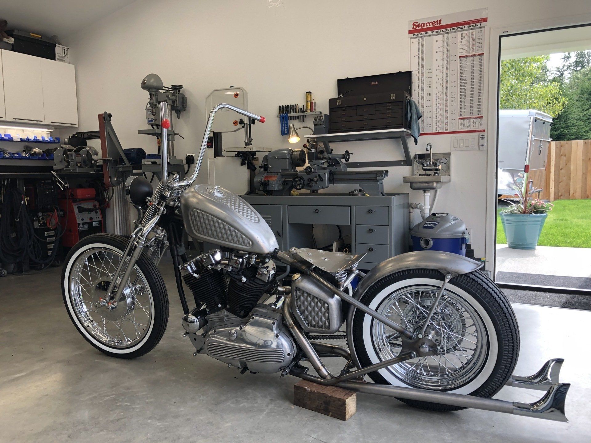 A silver motorcycle is parked in a garage.