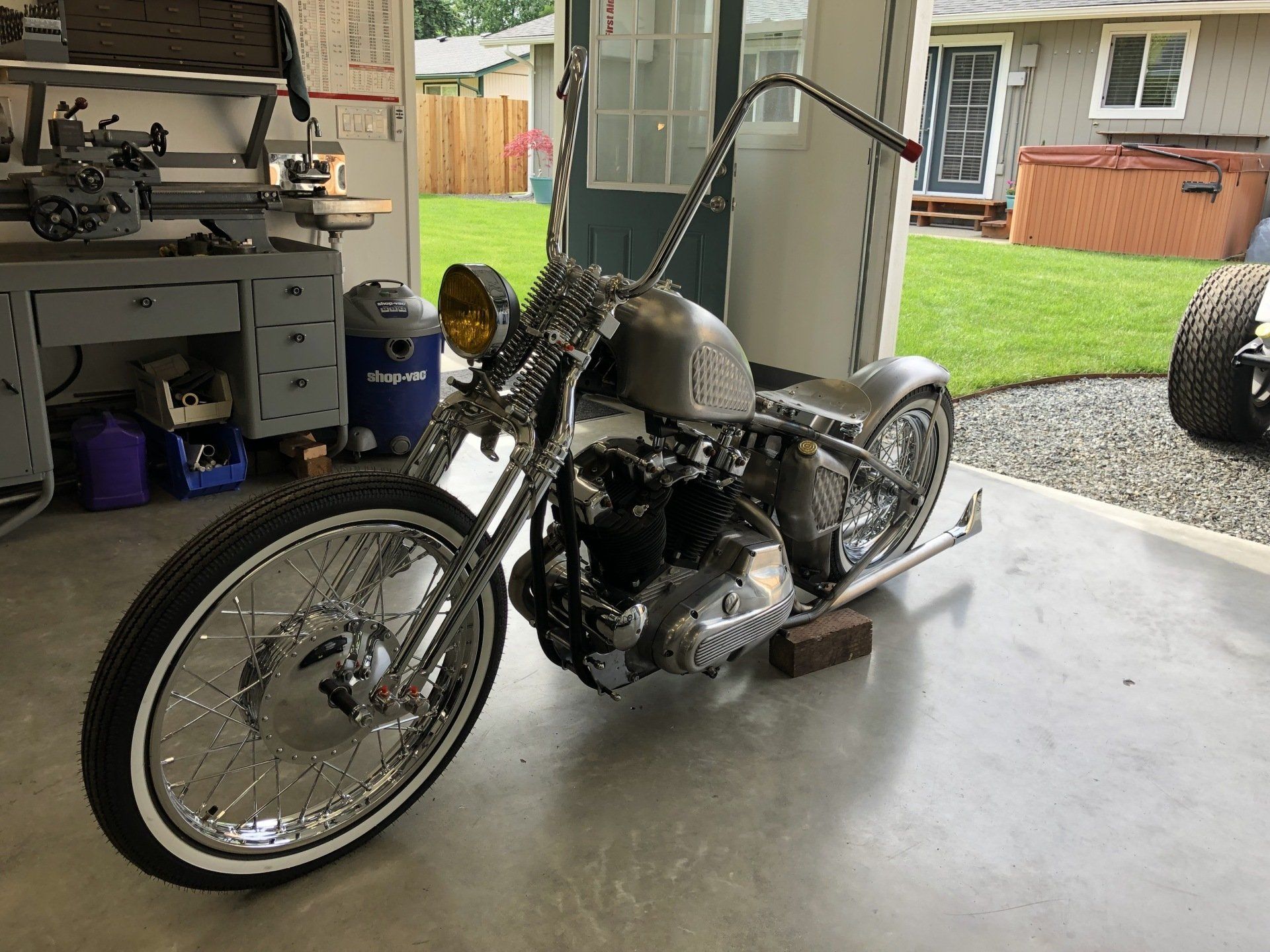 A motorcycle is parked in a garage next to a lathe