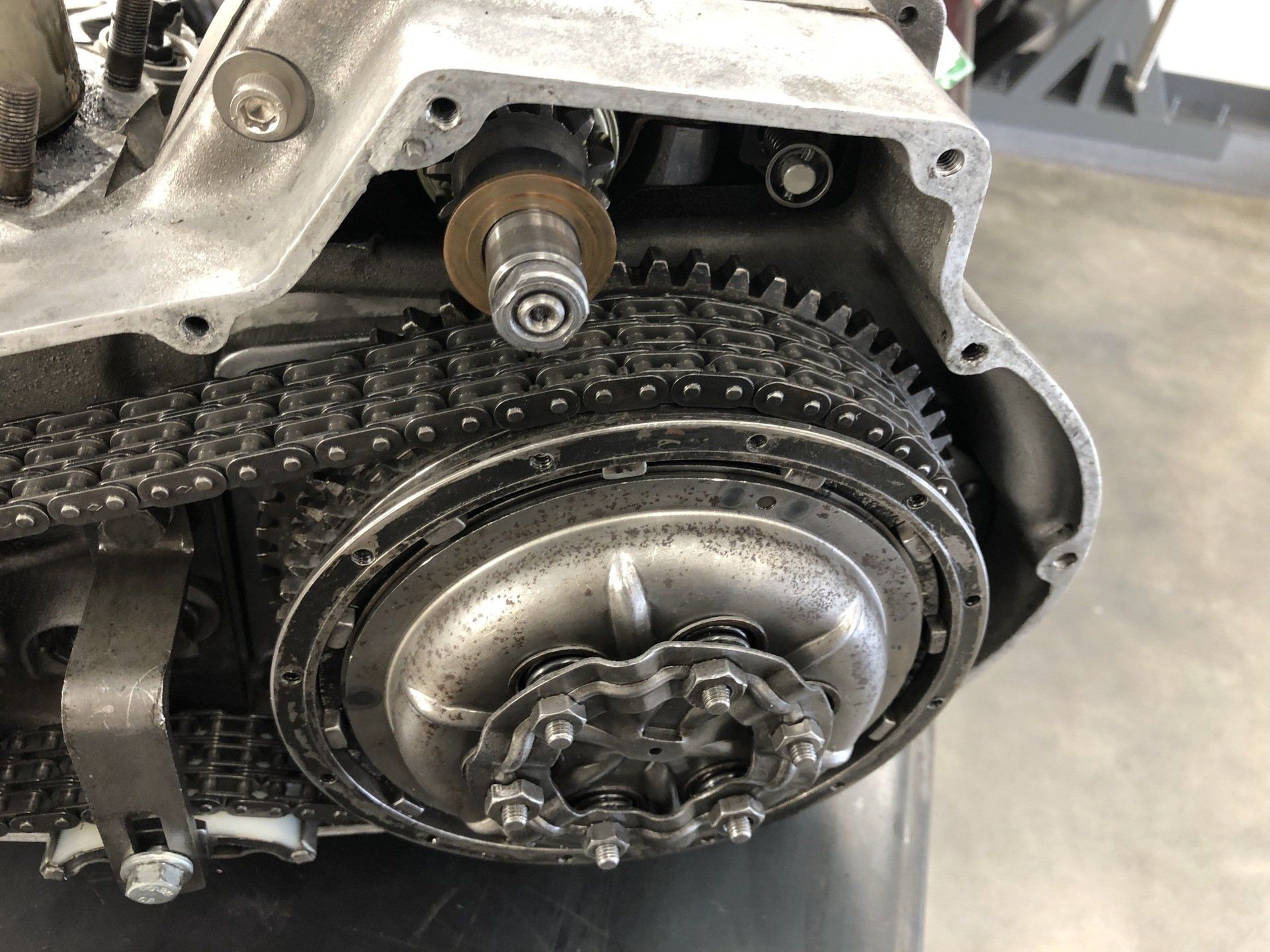 A close up of a motorcycle engine with gears and chains.