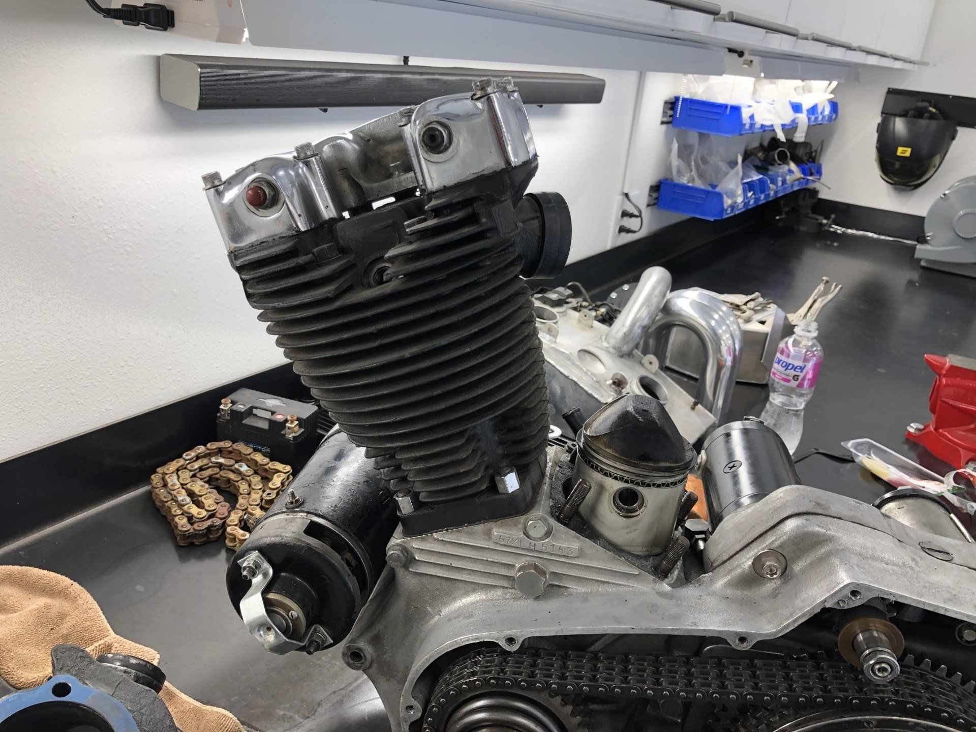 A motorcycle engine is sitting on a table in a garage.