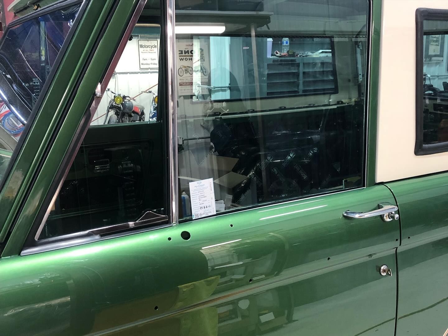 A green truck with a white top is parked in a garage.