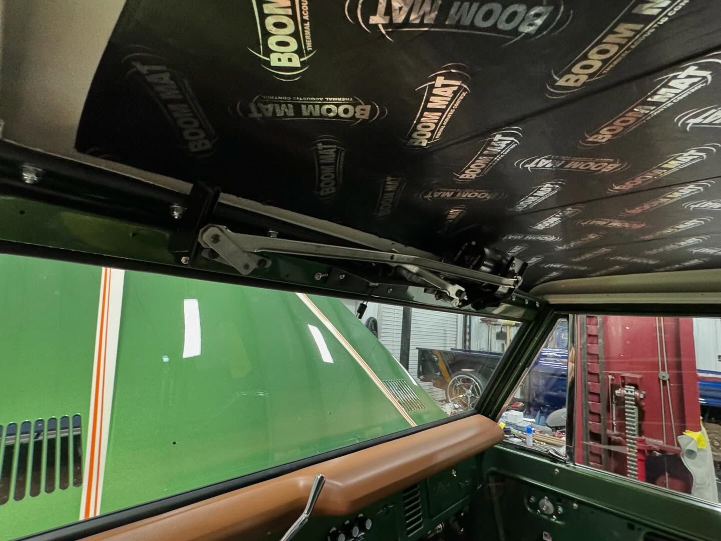 The roof of a green car is covered in boom mat