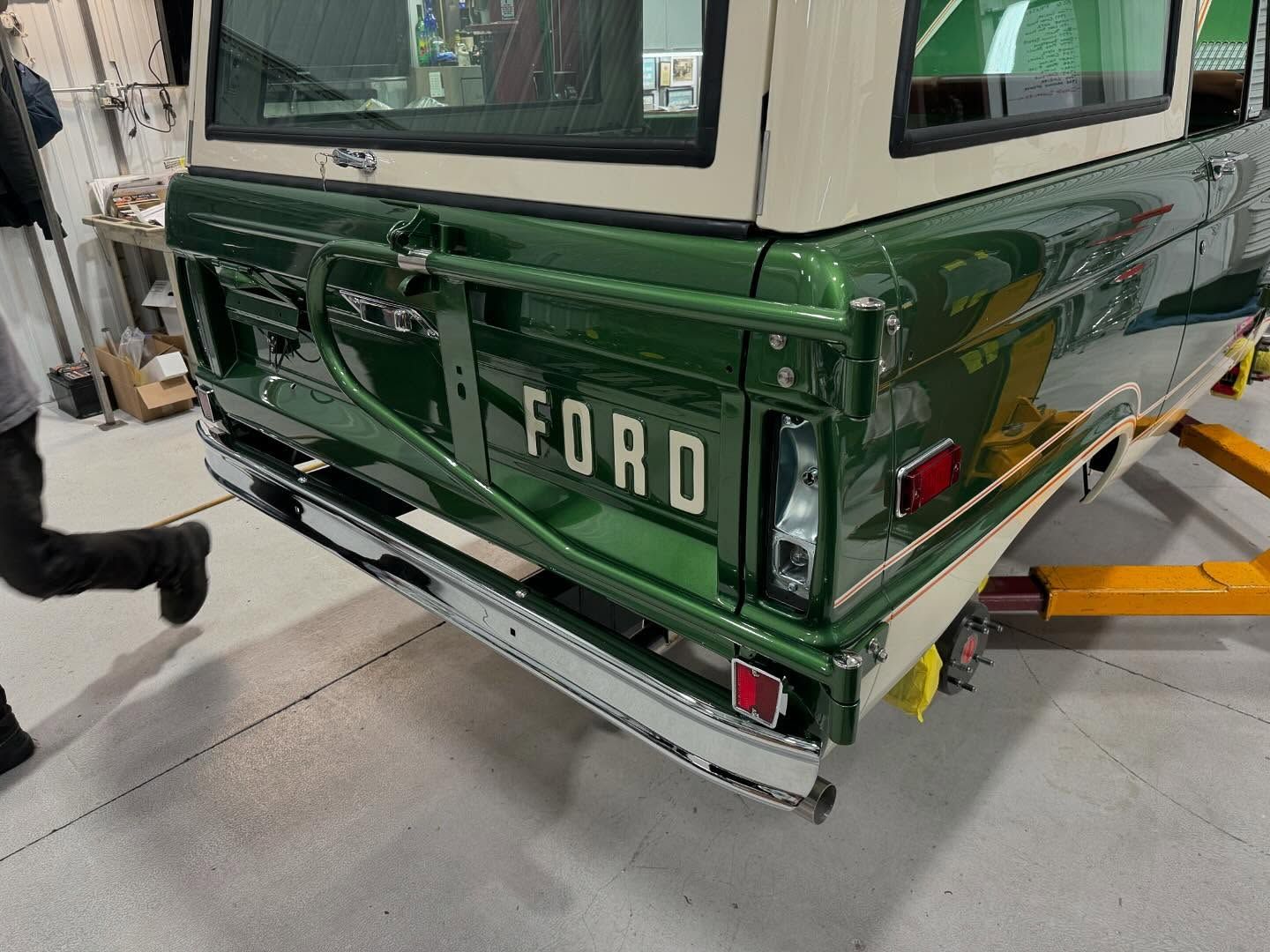 A green ford truck is sitting on a lift in a garage.