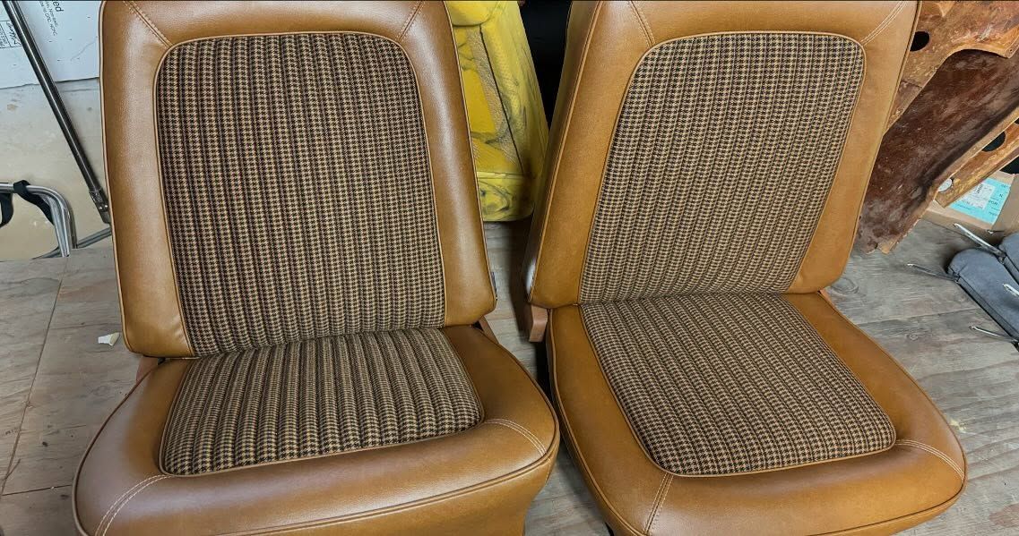 A pair of brown car seats are sitting next to each other on a wooden floor.