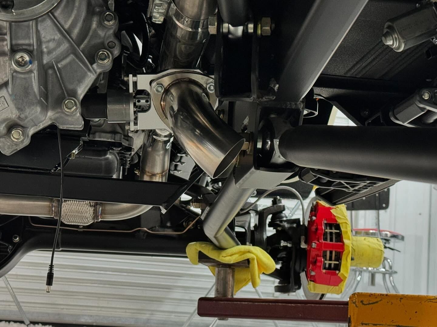 A close up of the underside of a car with a red brake caliper