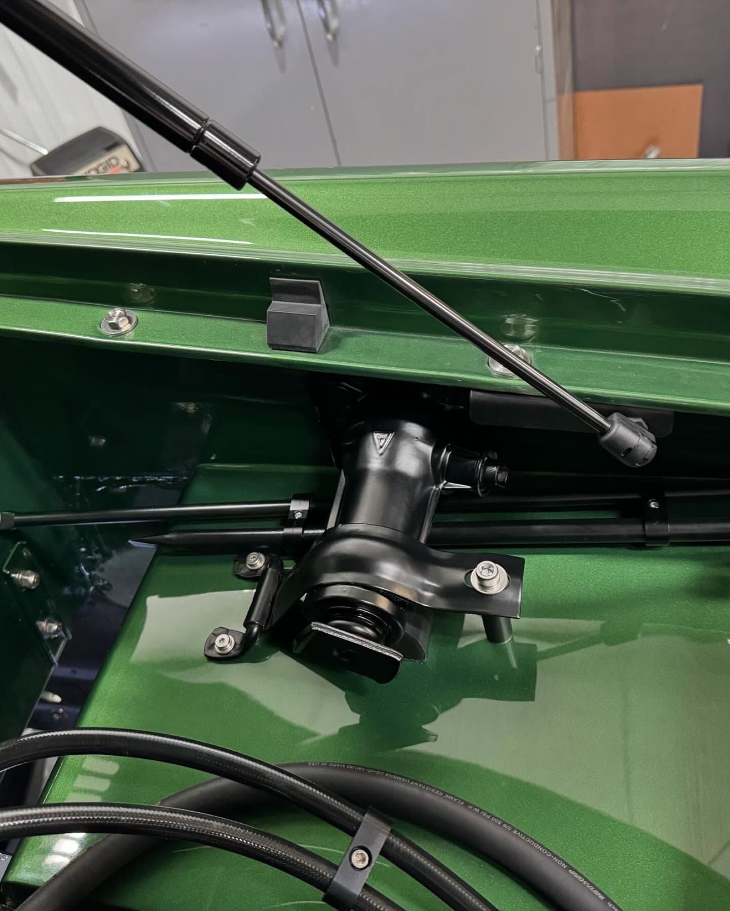 A close up of a green car with the hood open