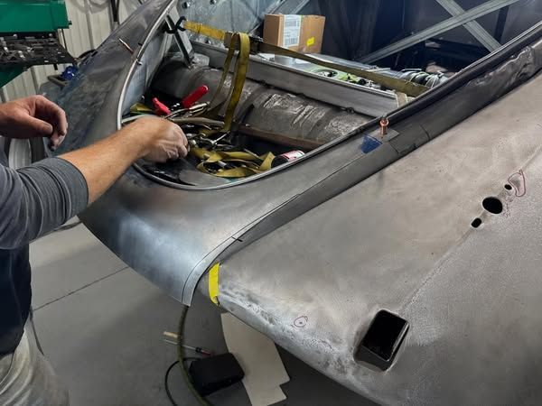 A man is working on the hood of a car