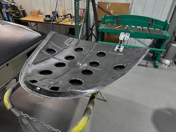 A piece of metal with holes in it is sitting on a table in a garage.