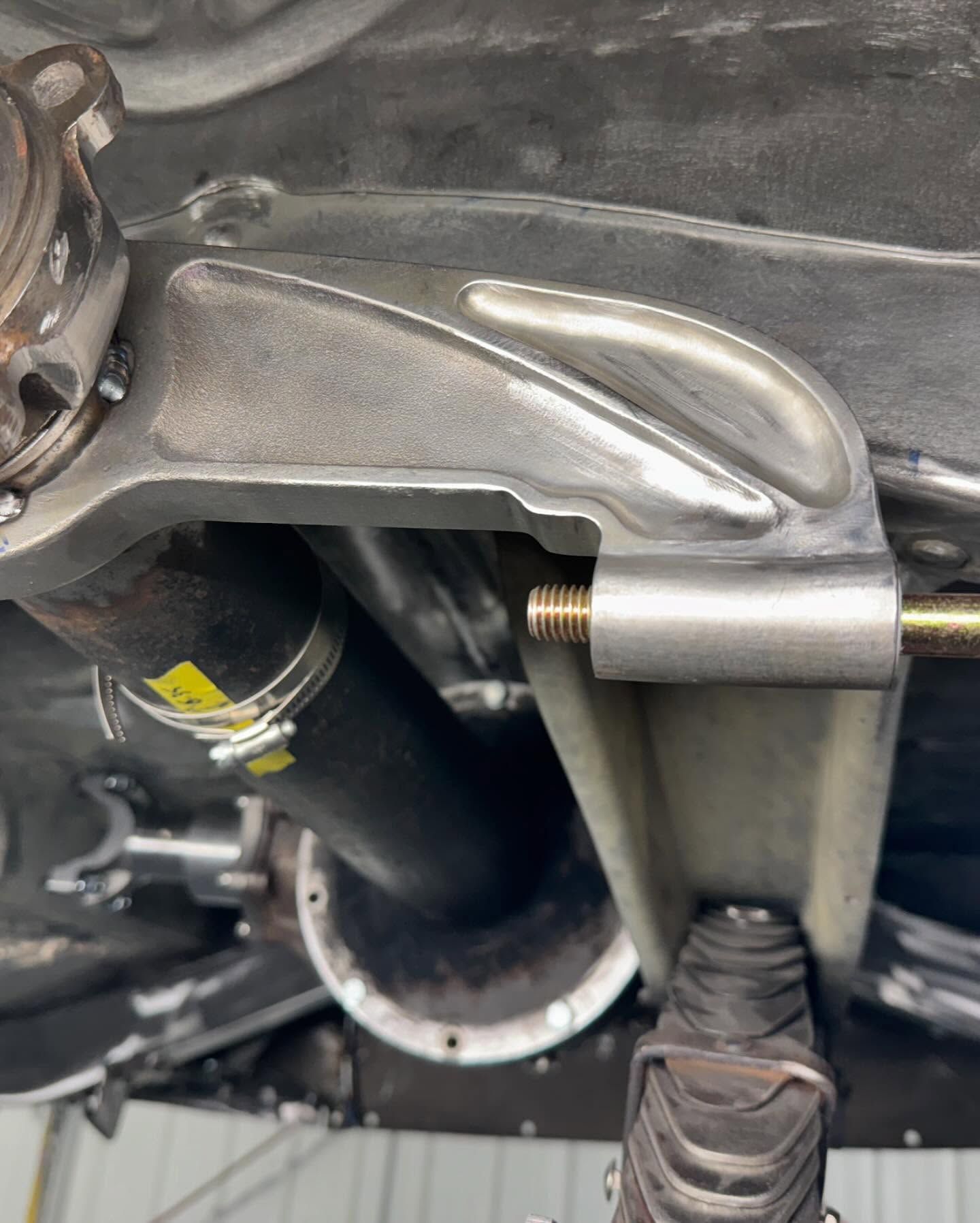 A close up of the underside of a car with a hose attached to it.