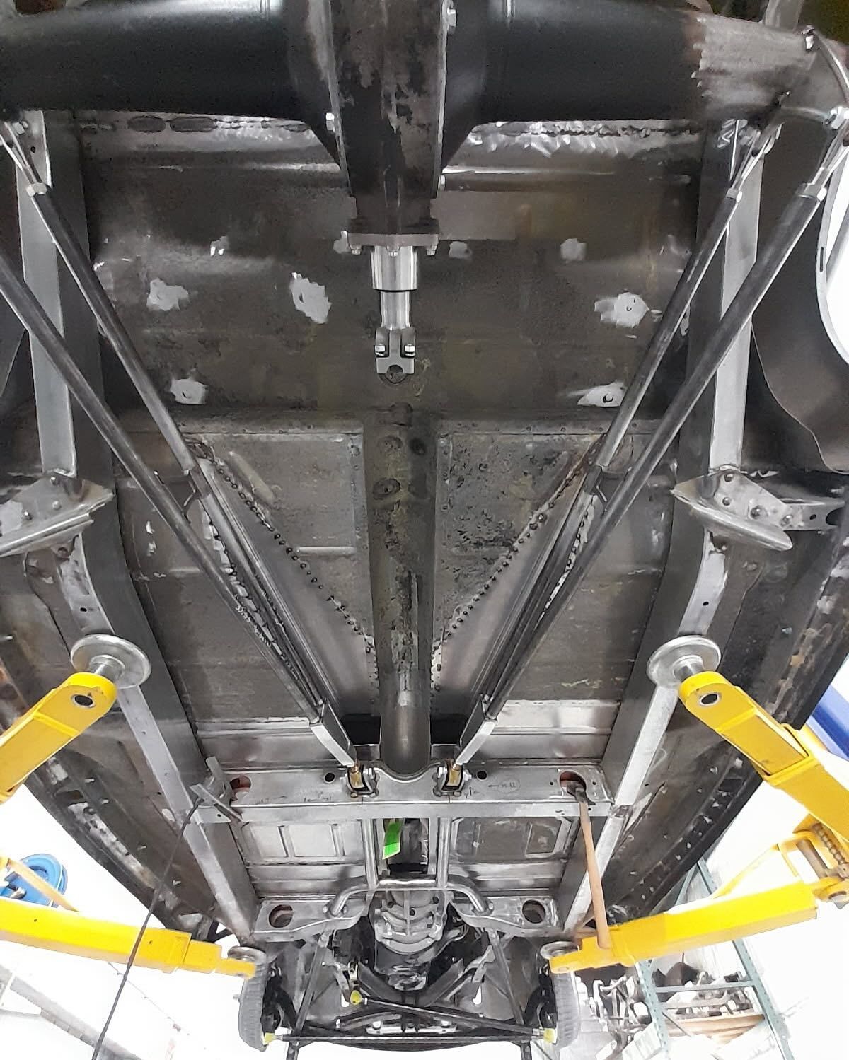 The underside of a car is being lifted on a lift.