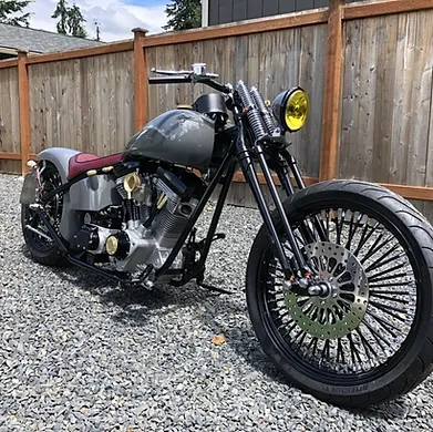 A motorcycle is parked on gravel in front of a wooden fence.