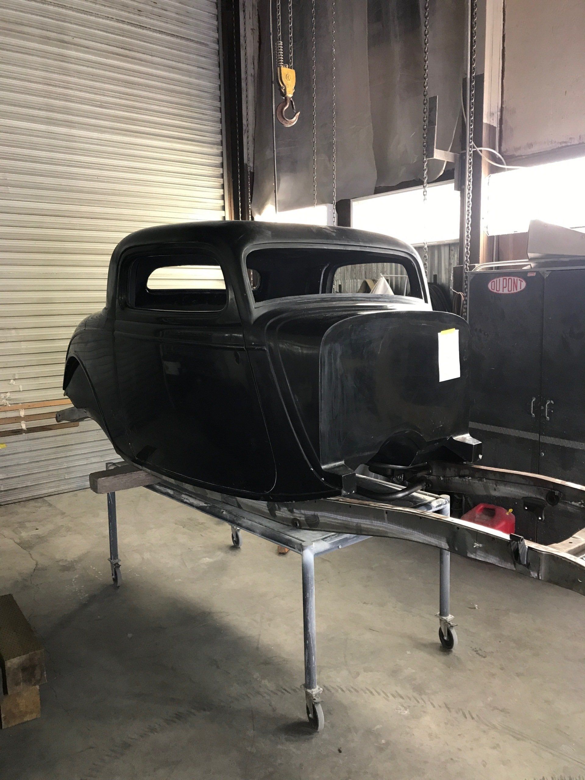A black car is sitting on a table in a garage.