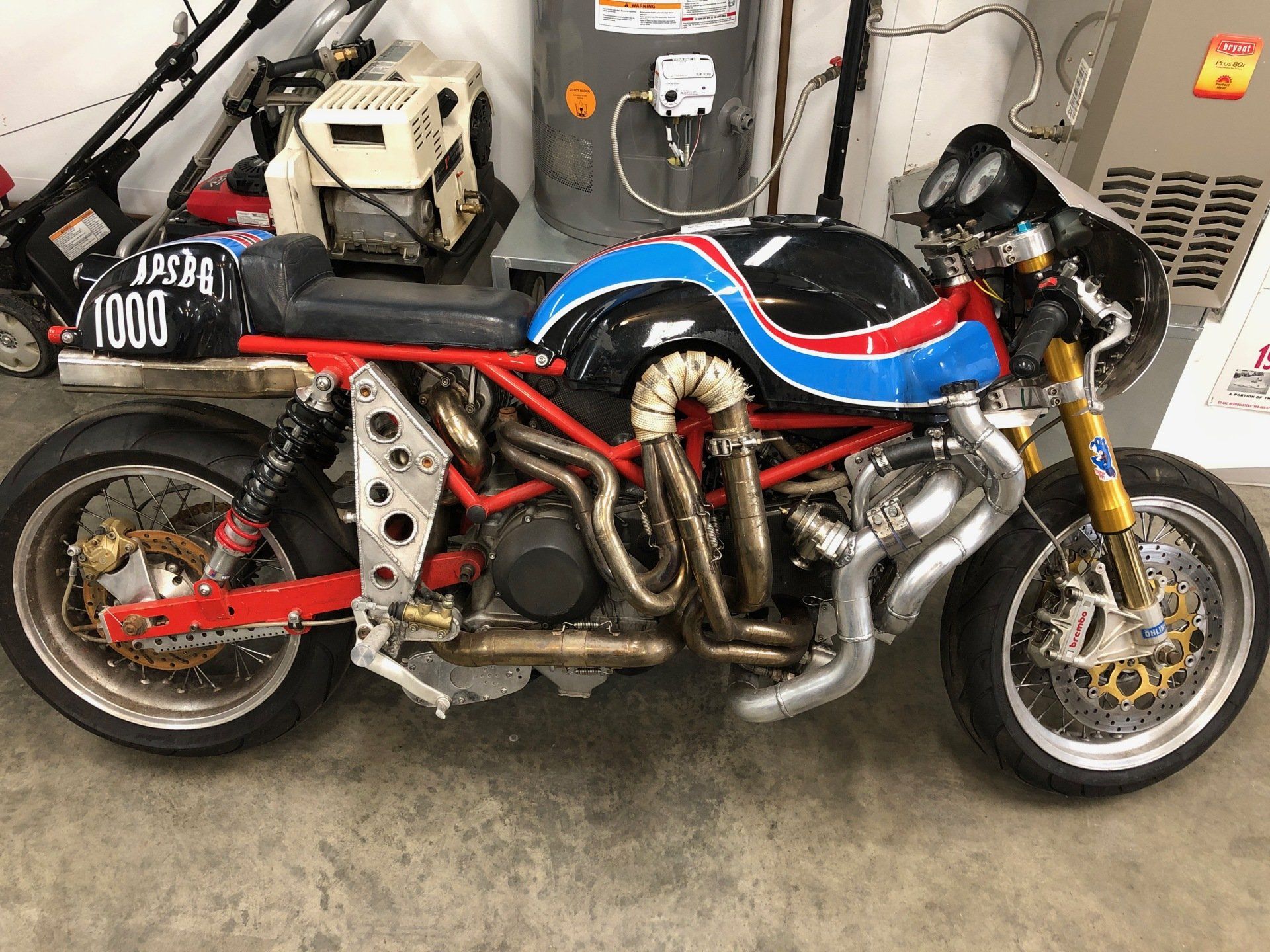 A red , white and blue motorcycle is parked in a garage.
