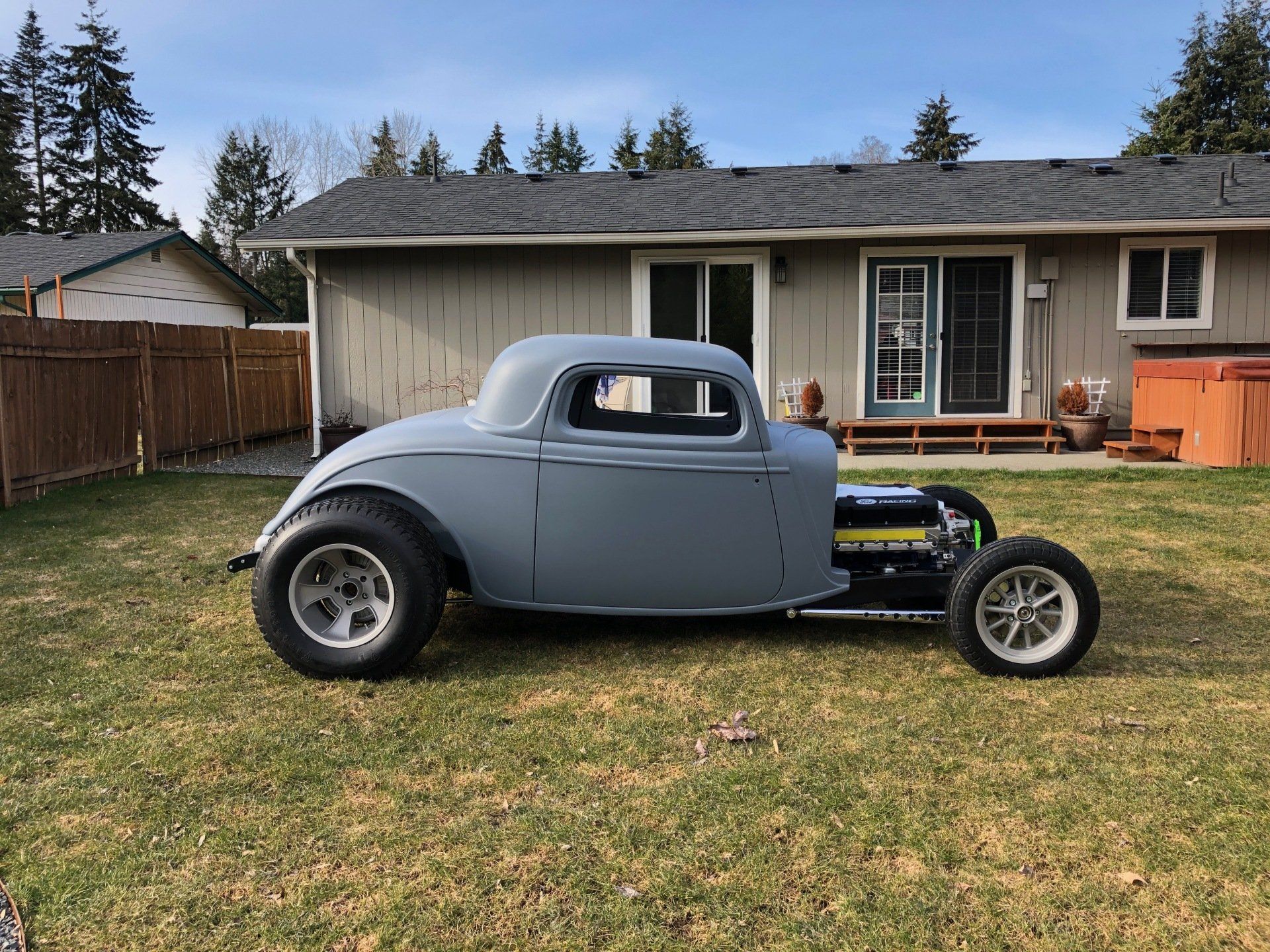 A gray car is parked in front of a house.