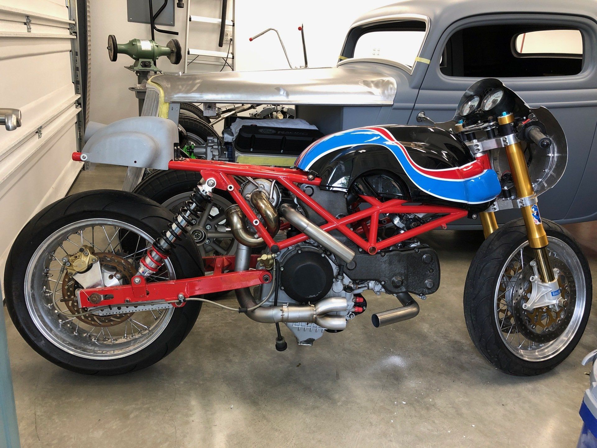 A motorcycle is parked in a garage next to a car