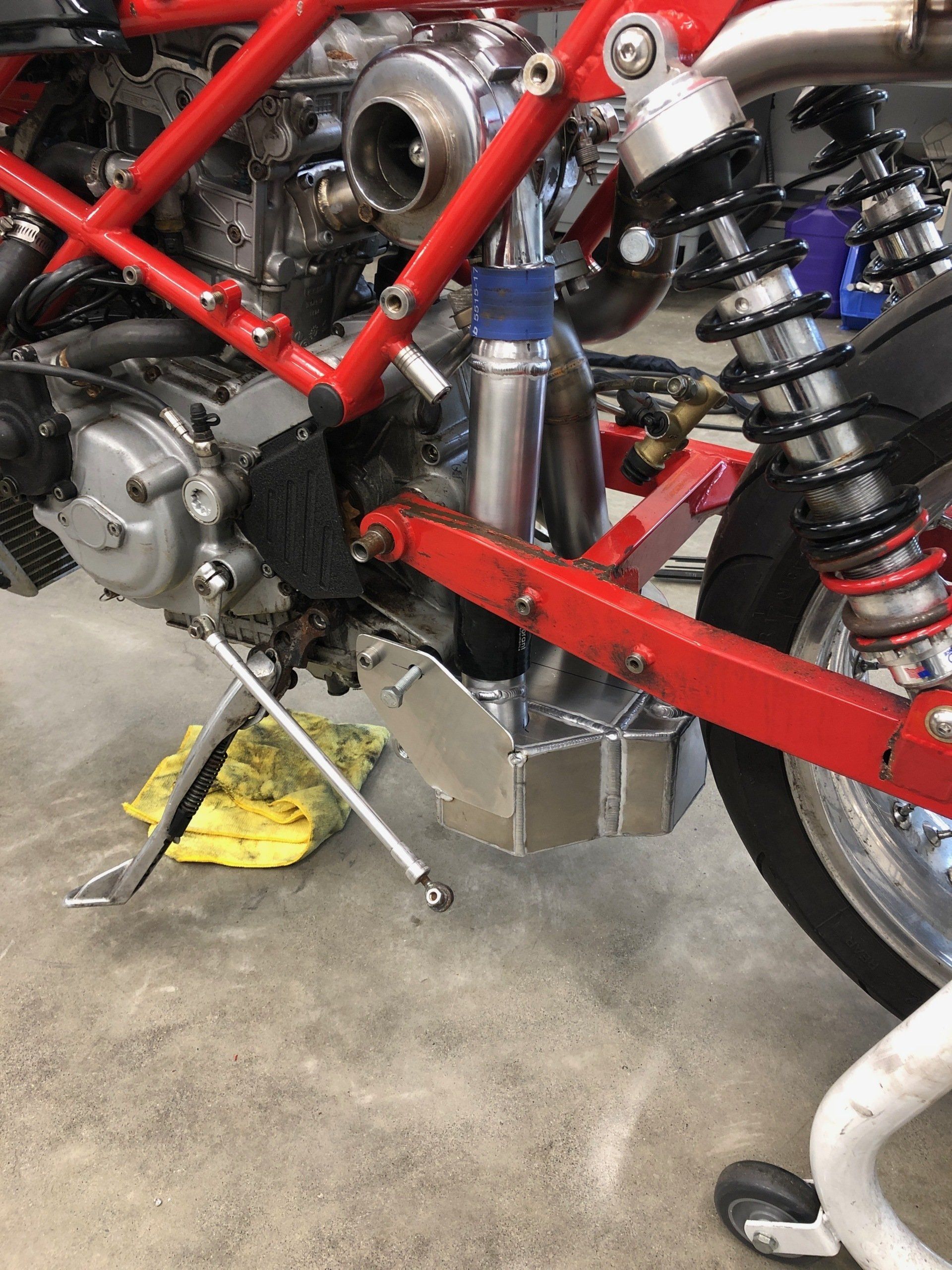 A red motorcycle is sitting on the ground in a garage.
