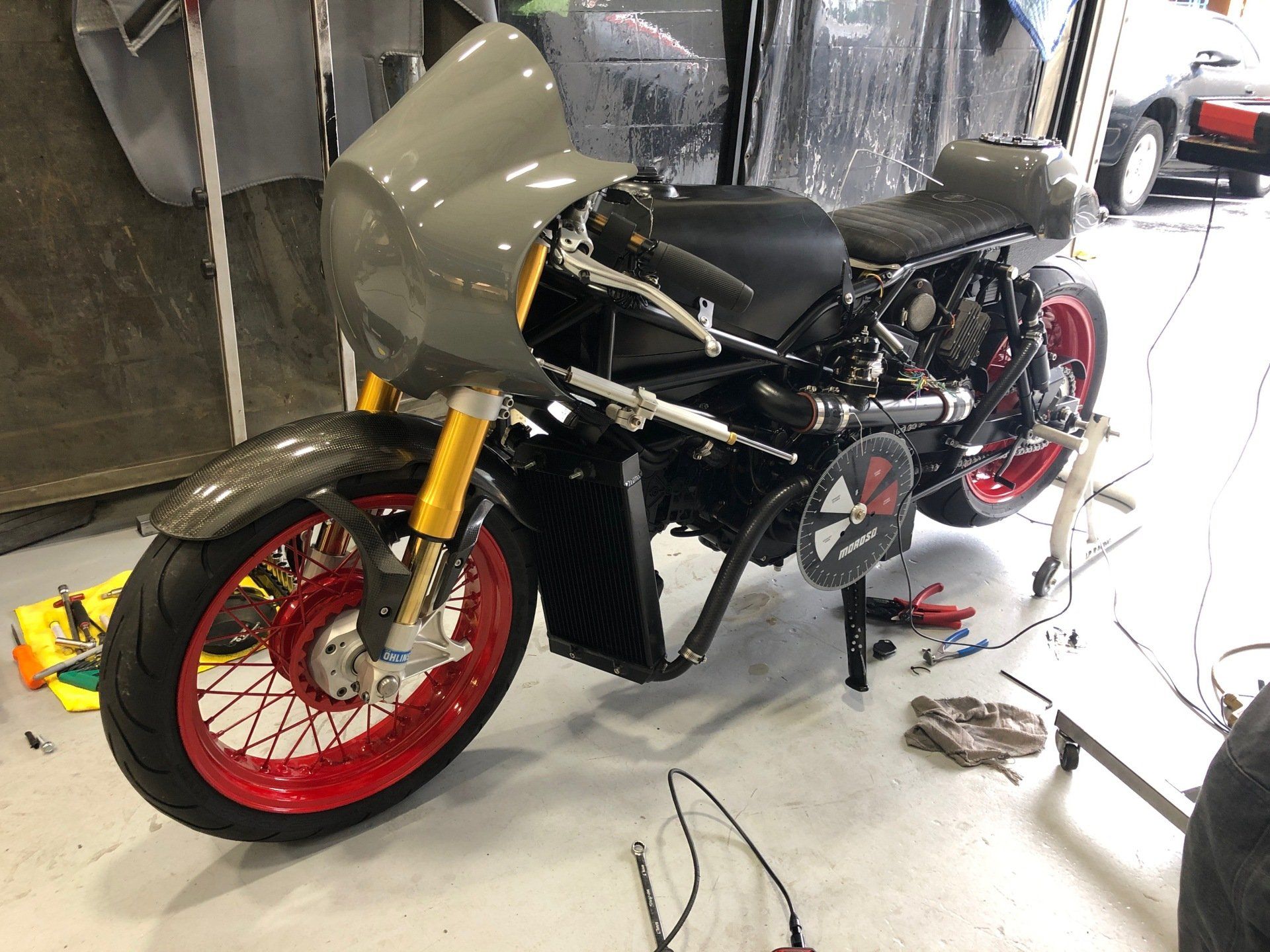 A black motorcycle with red wheels is sitting in a garage.