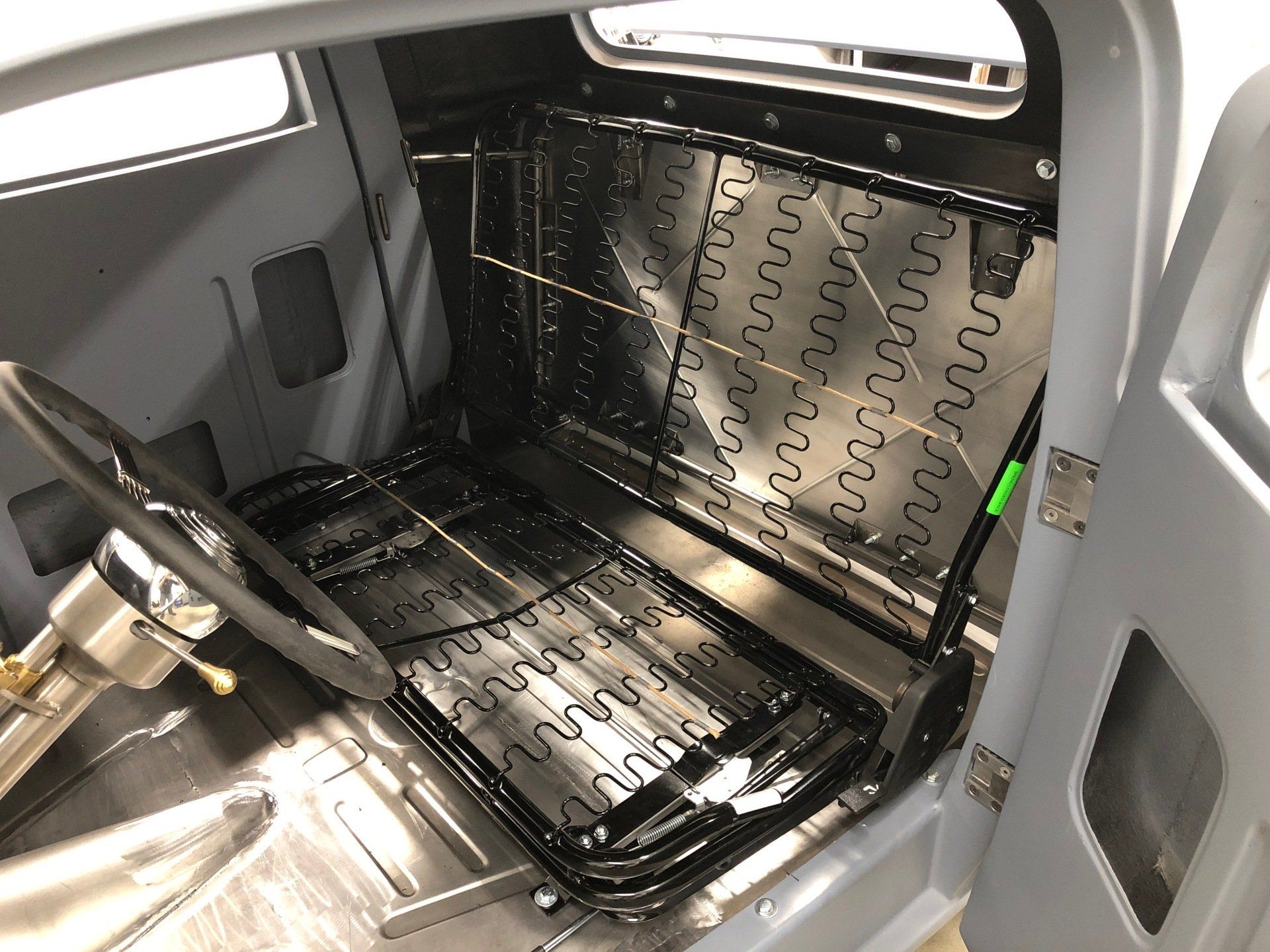 The inside of a car with a seat and a steering wheel.