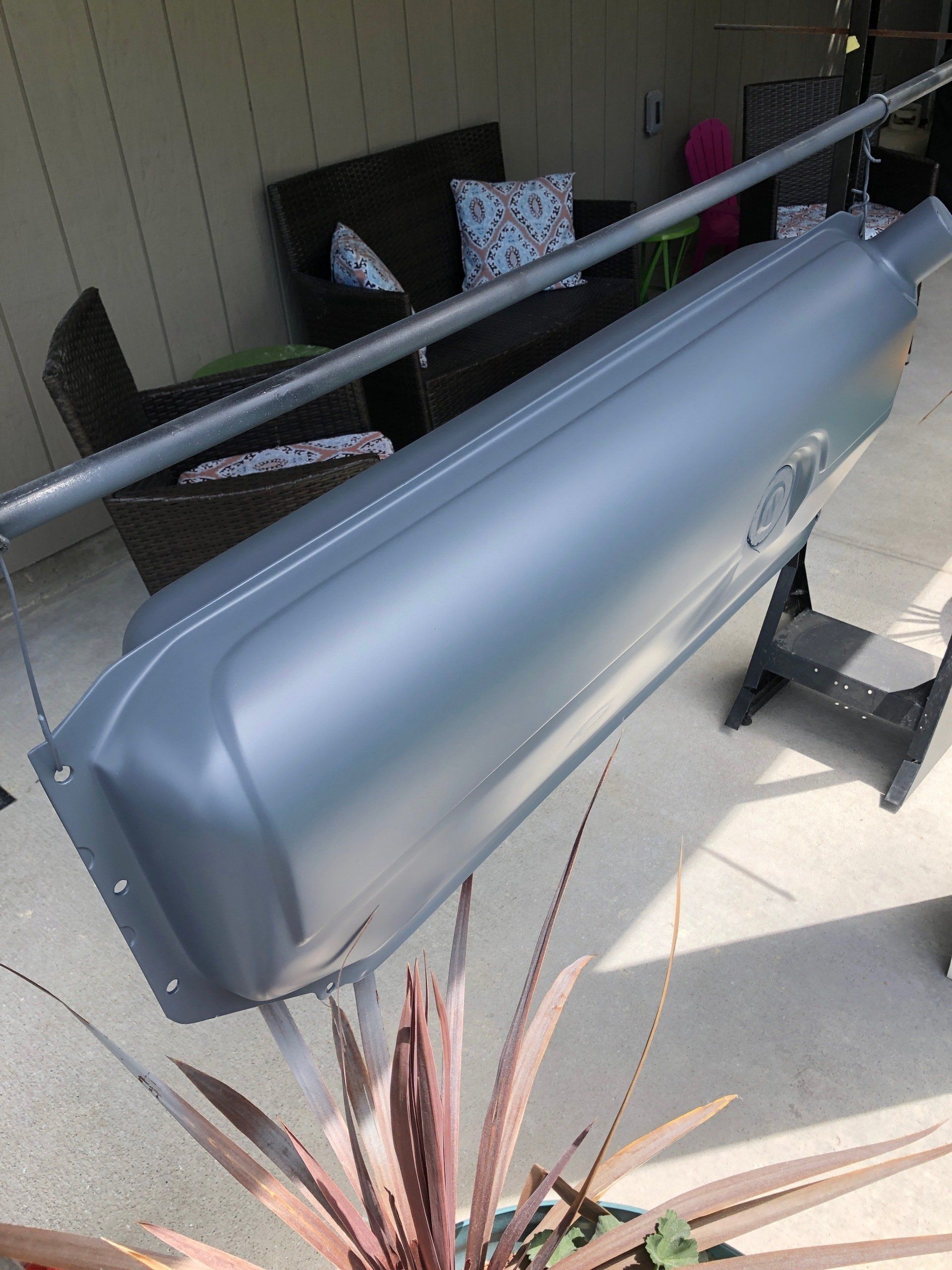 A large metal object is sitting on a patio next to a plant.