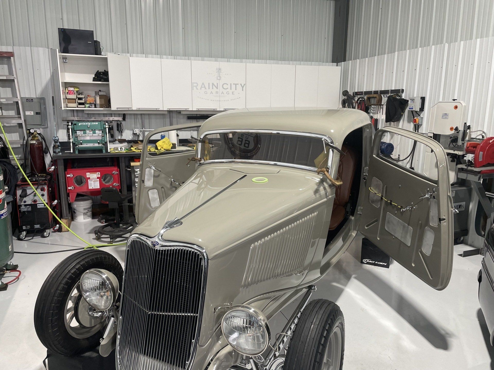 An old car is parked in a garage with its doors open