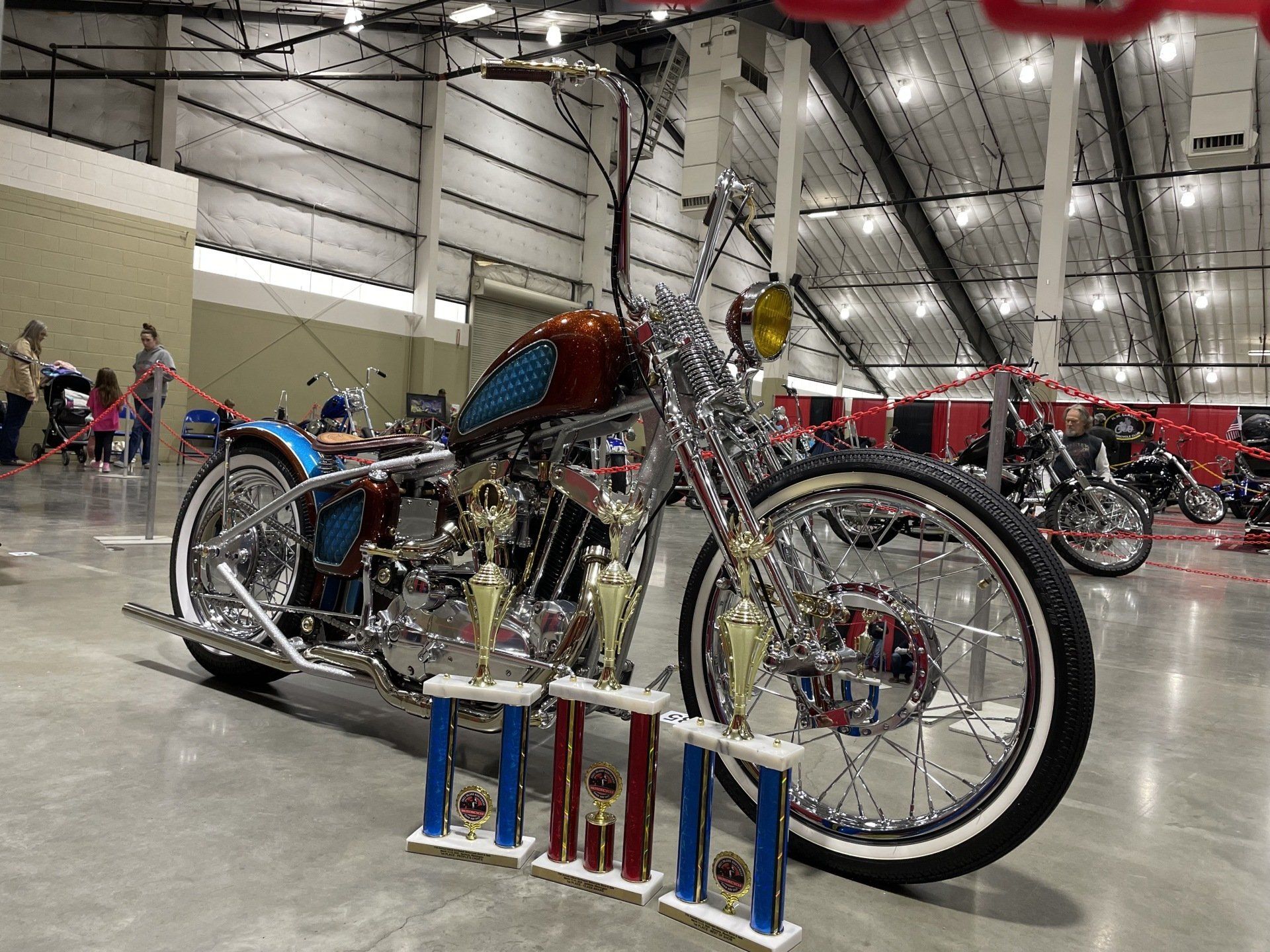 A motorcycle is parked in a warehouse next to trophies.
