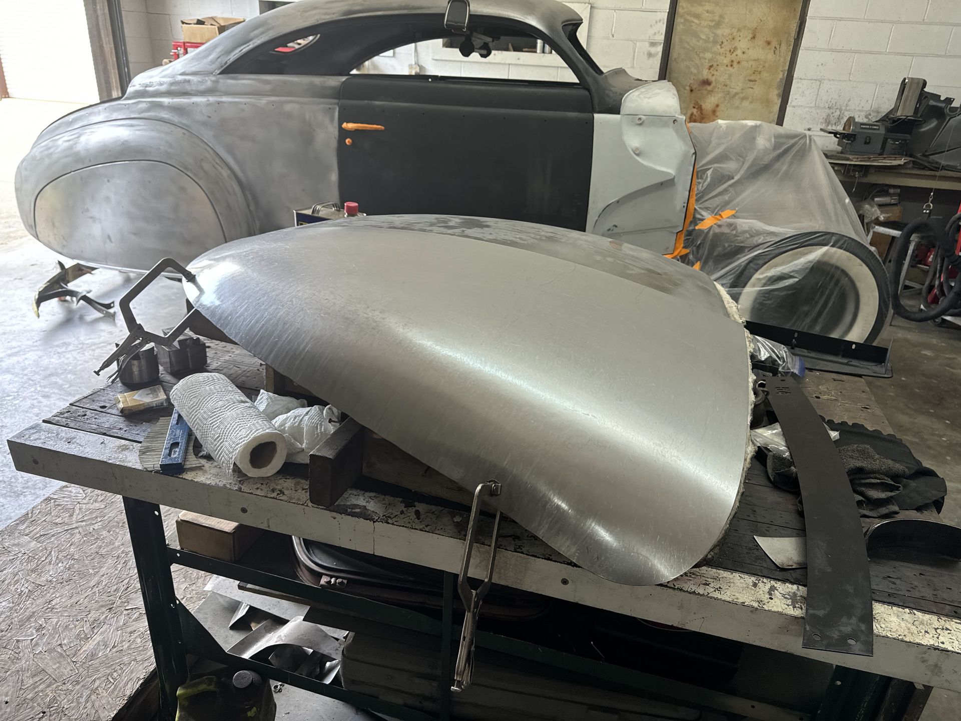 A silver car is sitting on top of a table in a garage.