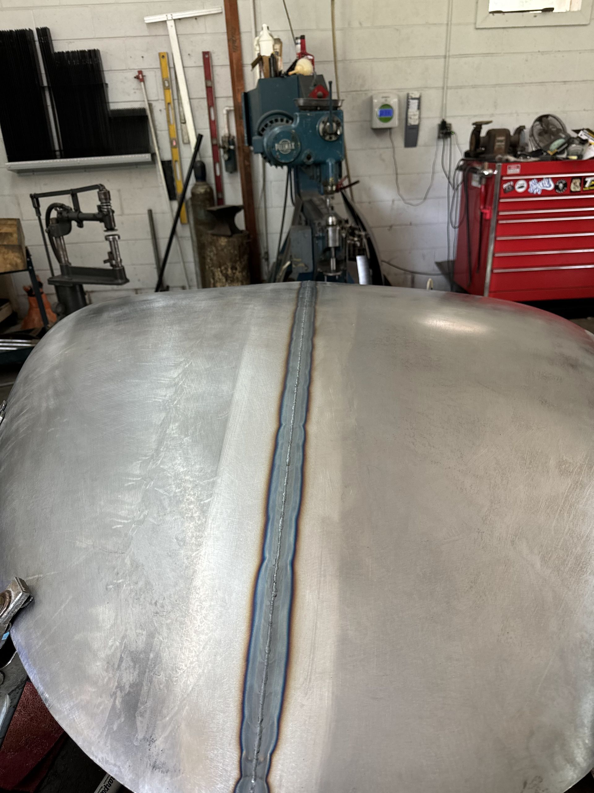 A large metal object is sitting in a garage next to a machine.