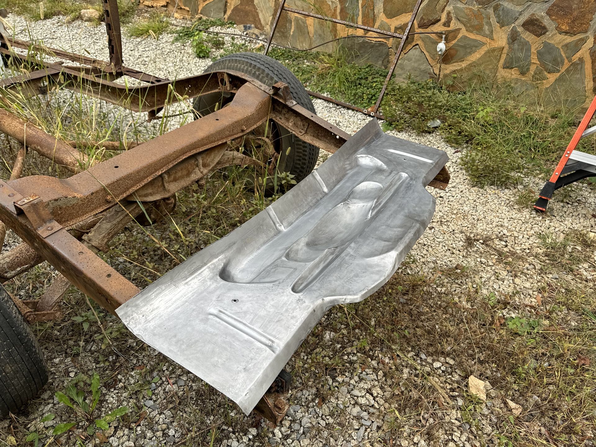 A piece of metal is sitting on the ground next to a metal frame.