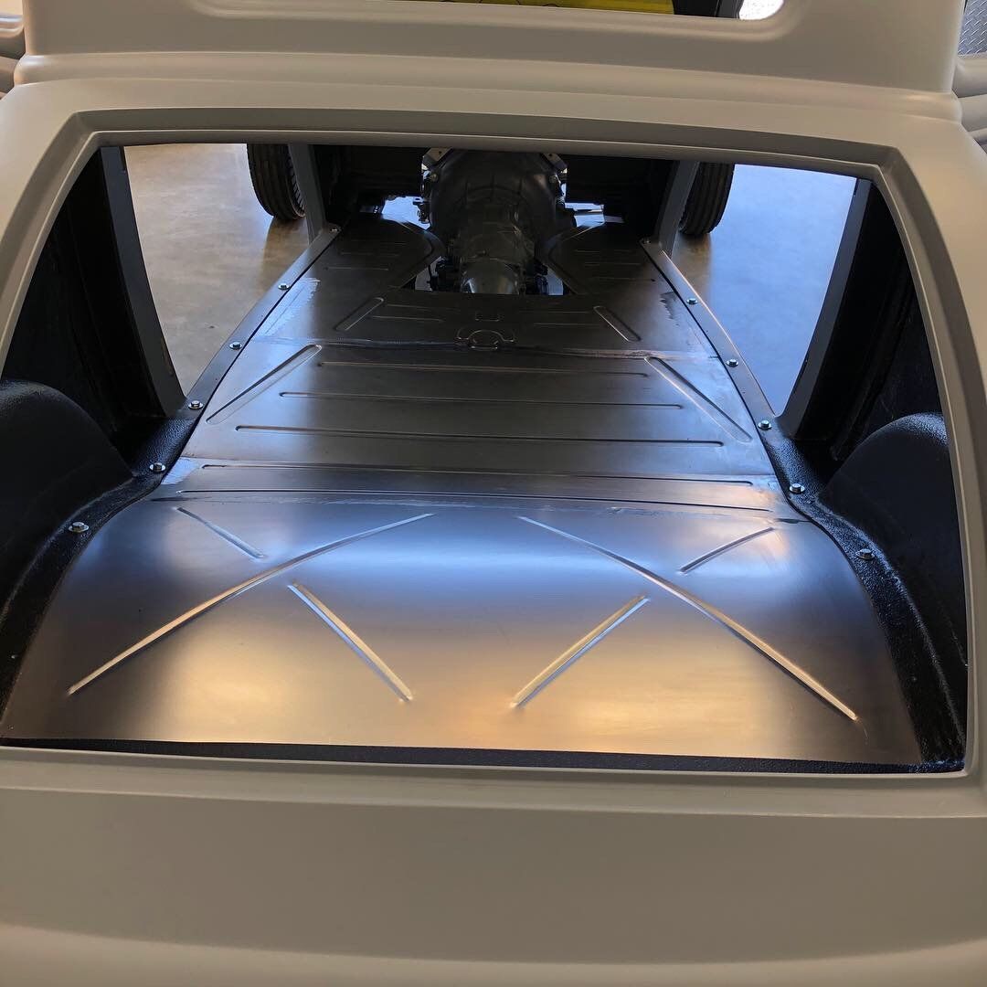 The back of a white car with a stainless steel tray on the floor.