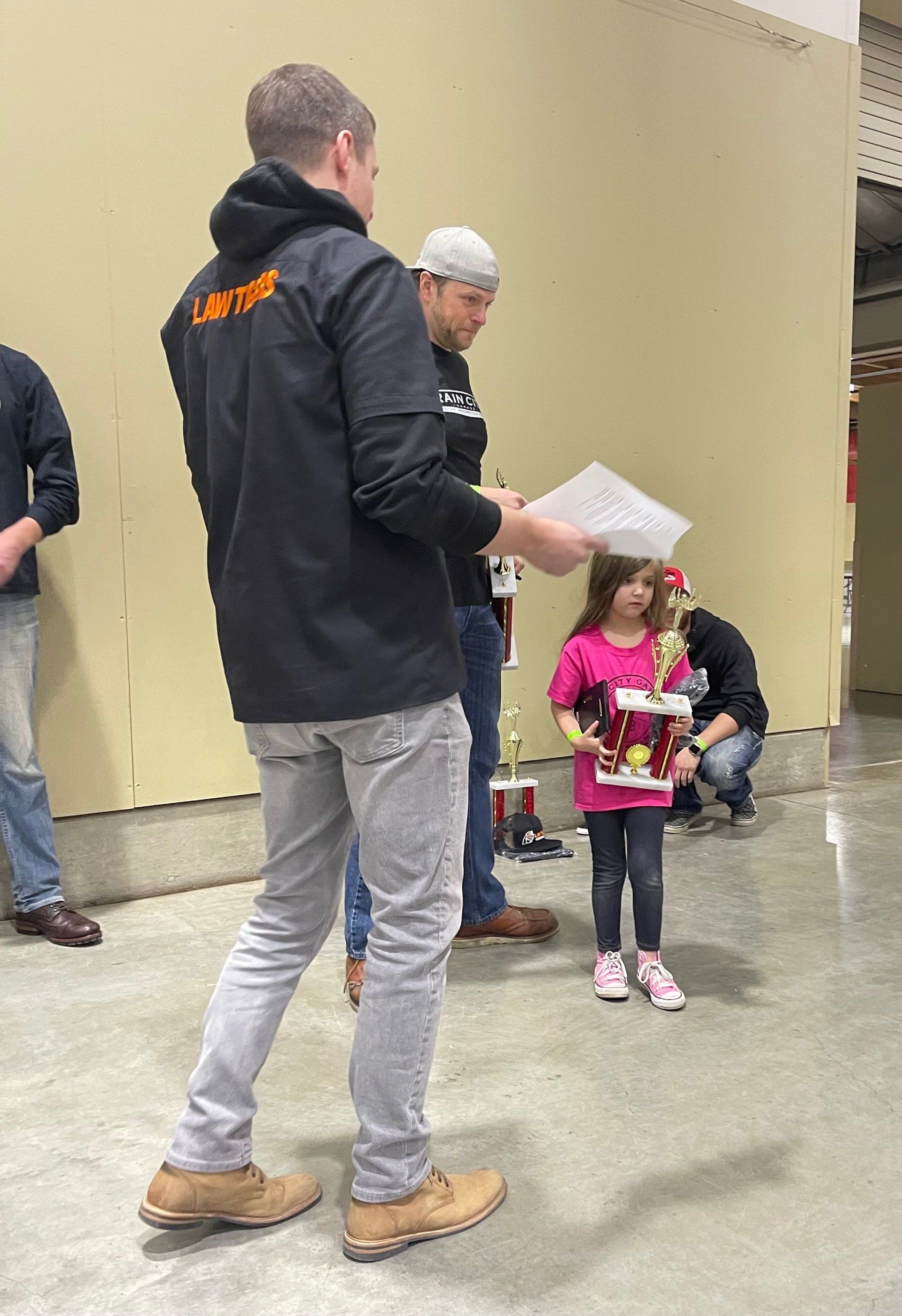 A man is standing next to a little girl holding a drum.