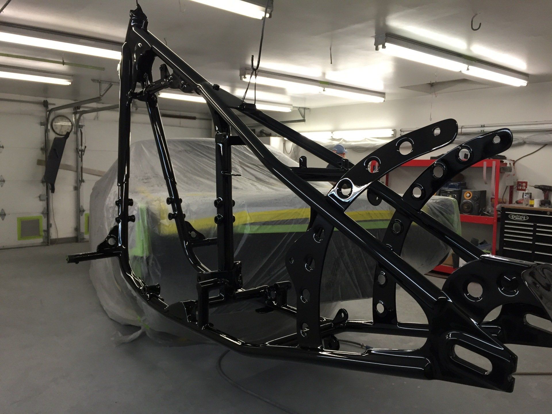 A motorcycle frame is being painted in a garage