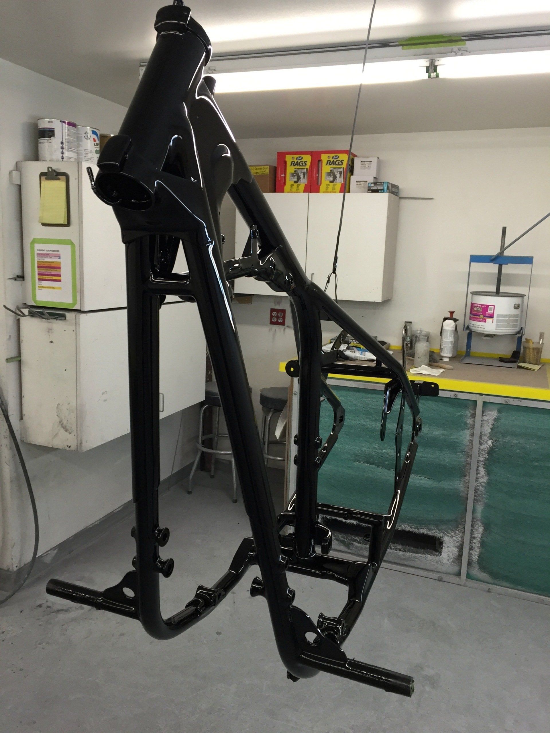 A motorcycle frame is hanging from the ceiling in a garage