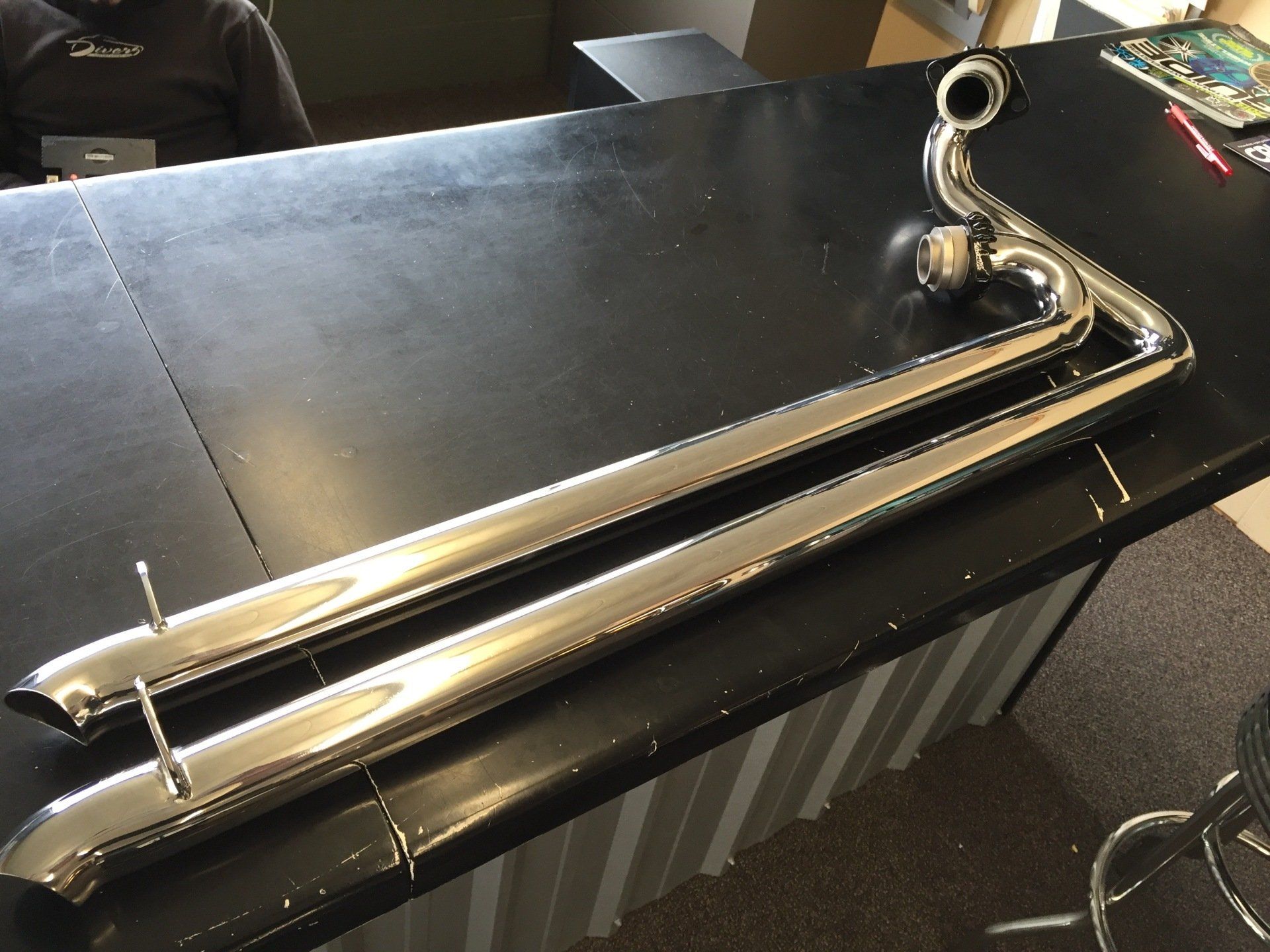 A pair of chrome pipes are sitting on a black table