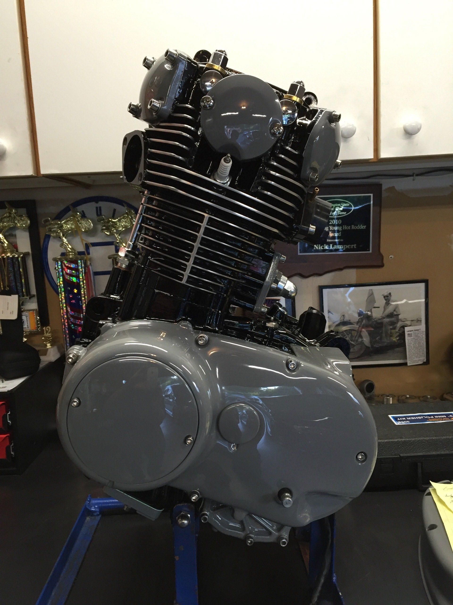 A motorcycle engine is sitting on a table in a garage.
