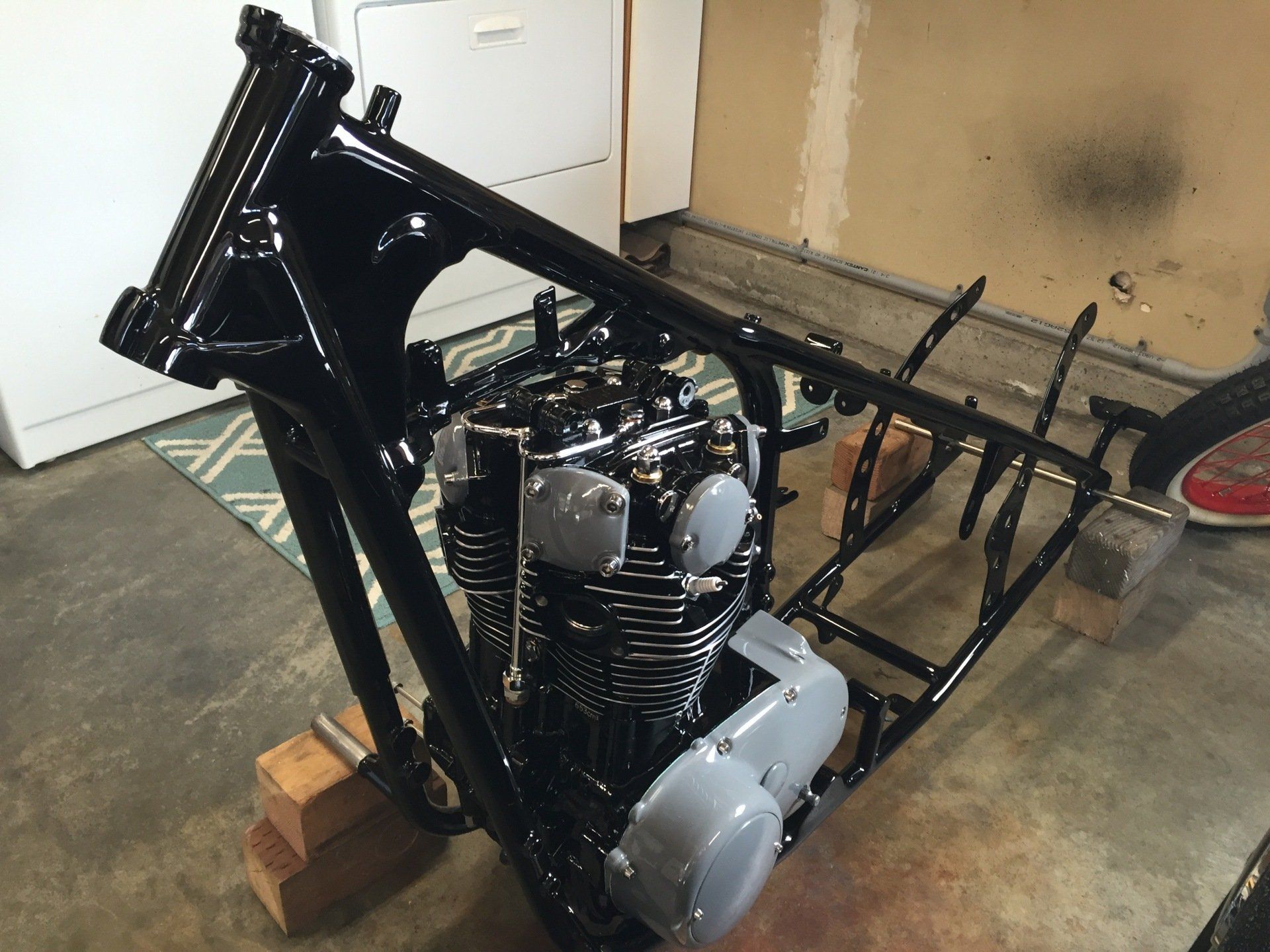 A motorcycle engine is sitting on top of a black frame.