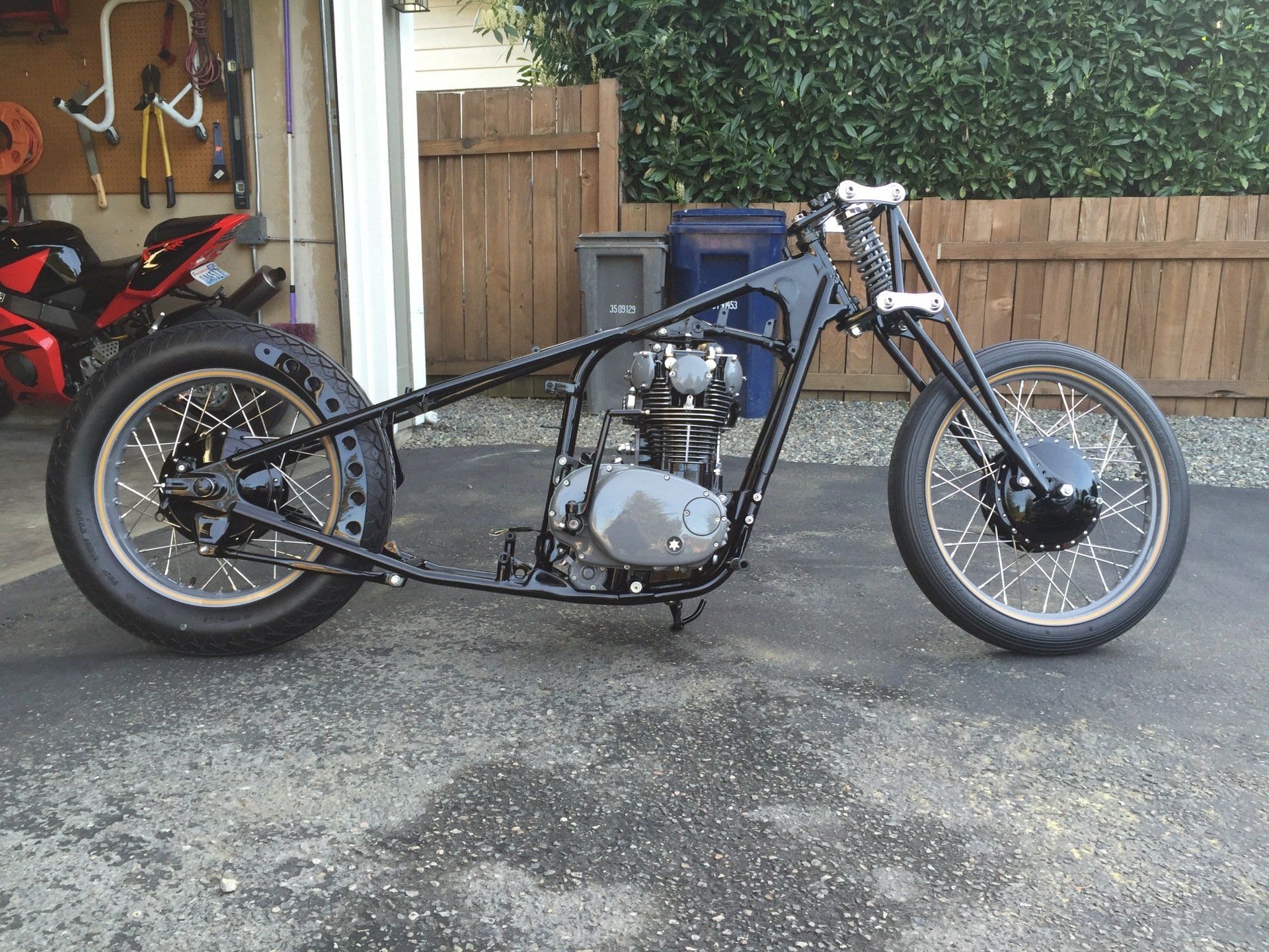 A black motorcycle is parked in front of a garage