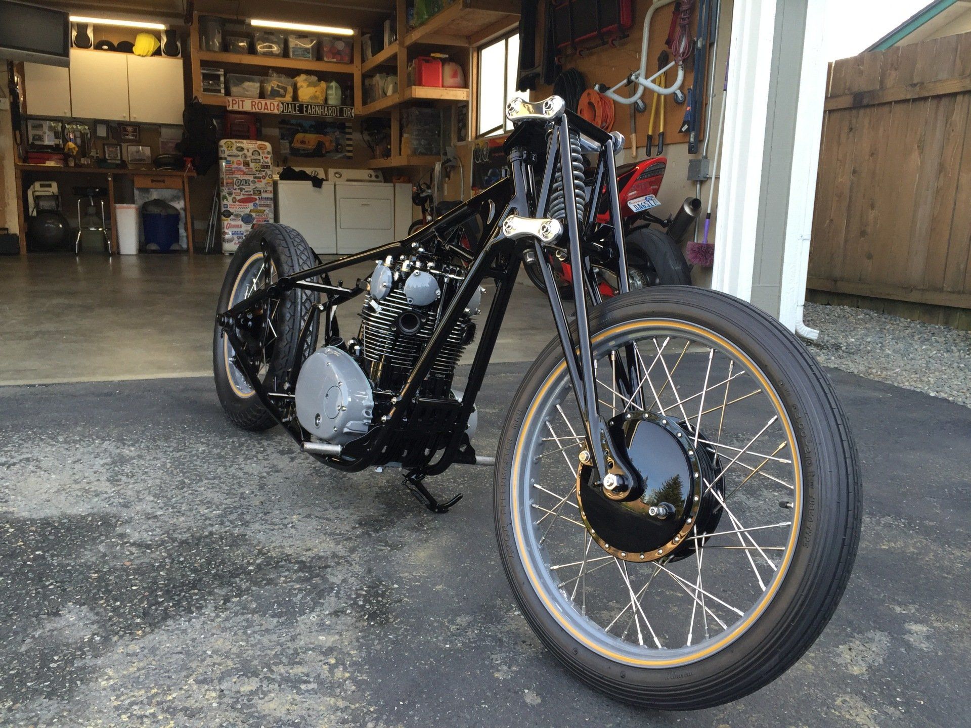 A black motorcycle is parked in front of a garage