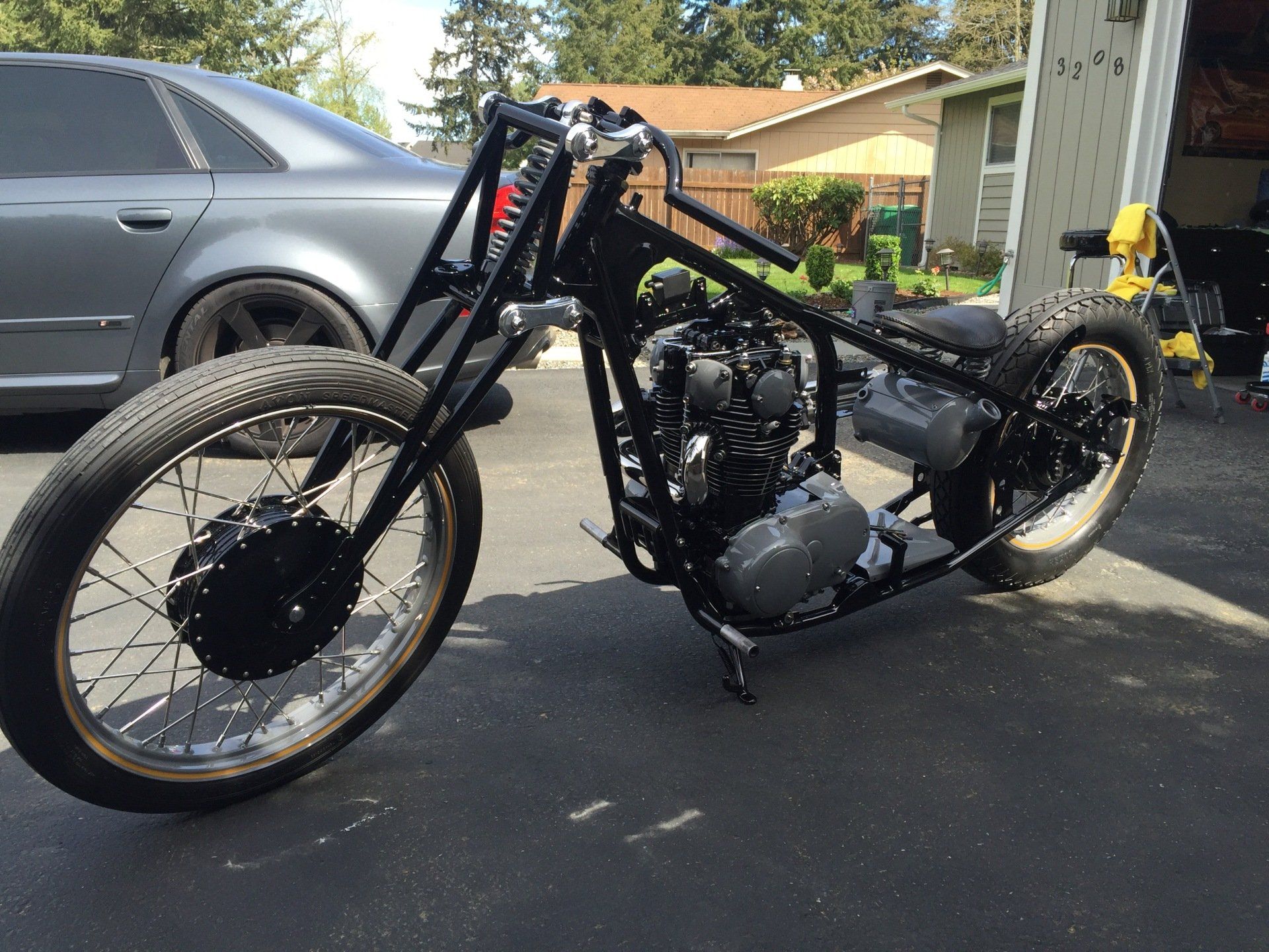 A motorcycle is parked in a driveway next to a car.