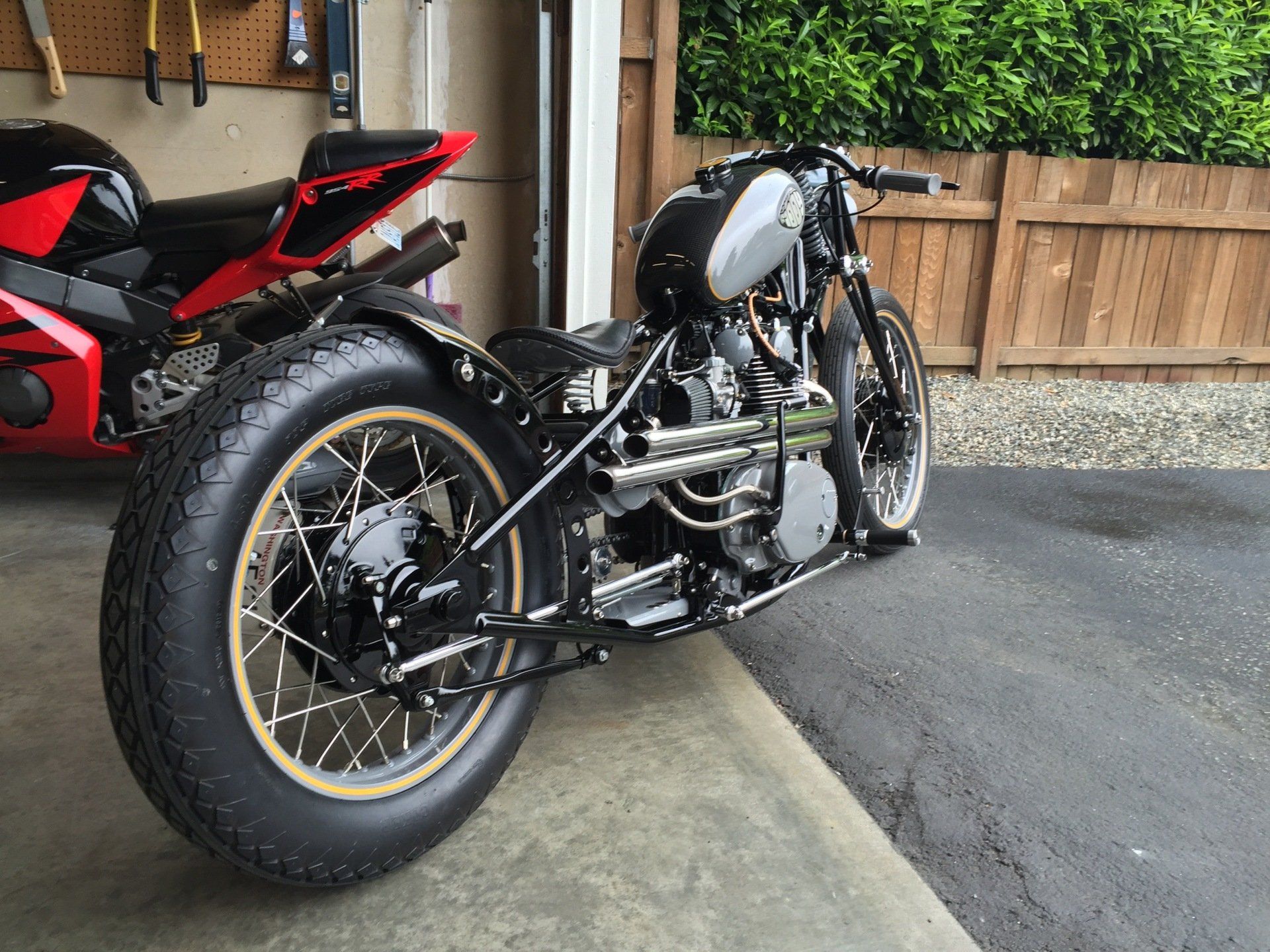 A motorcycle is parked in a garage next to a red motorcycle