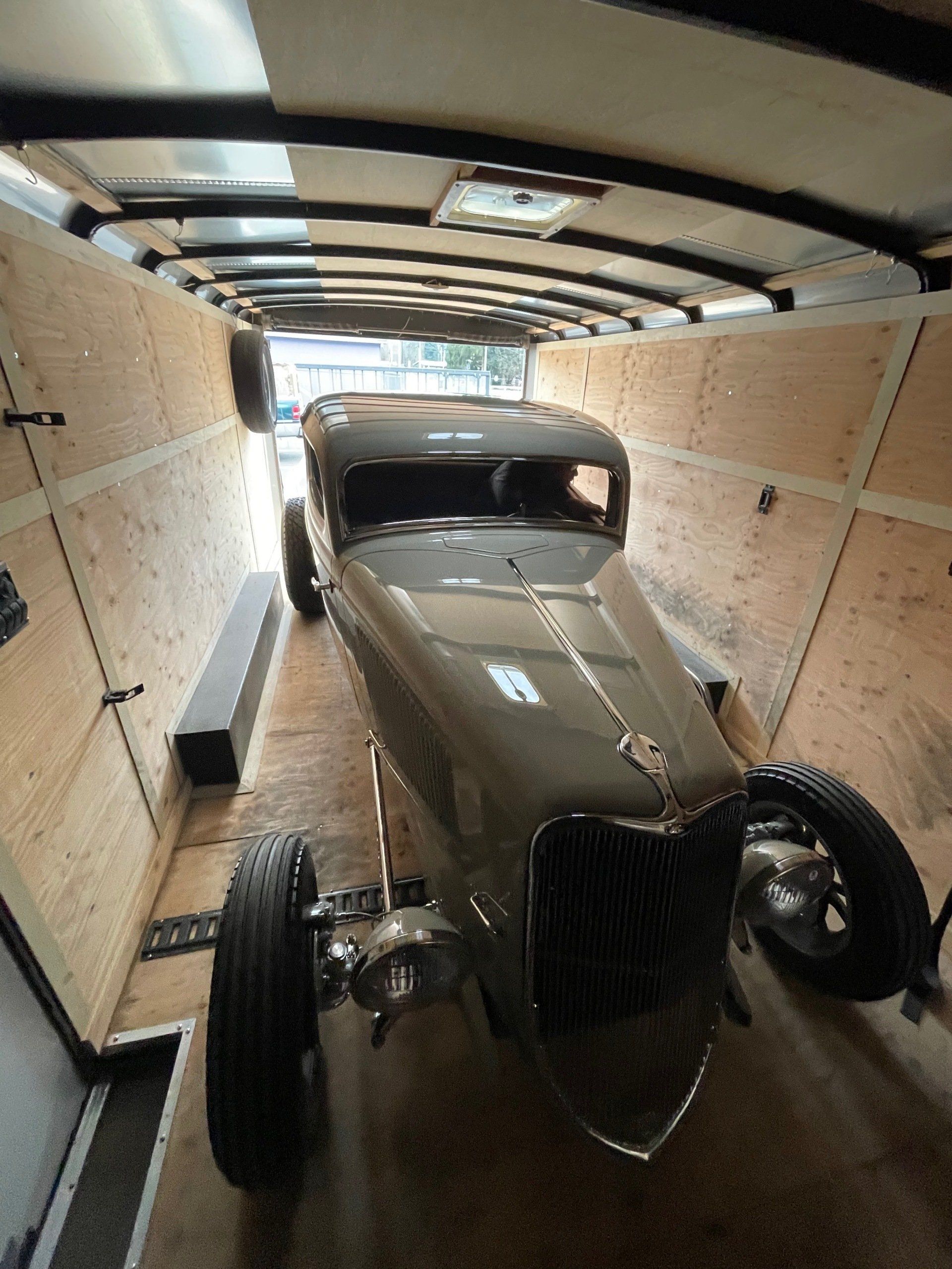 An old car is sitting inside of a trailer.