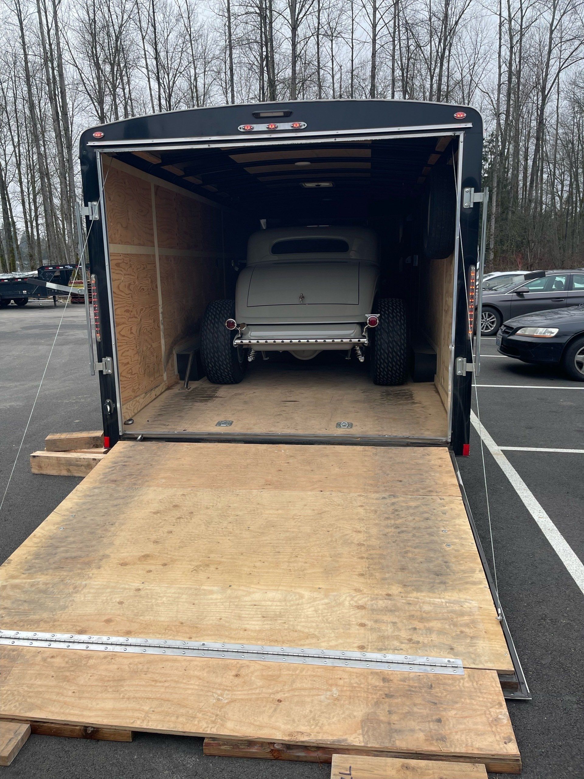 A car is sitting inside of a trailer in a parking lot