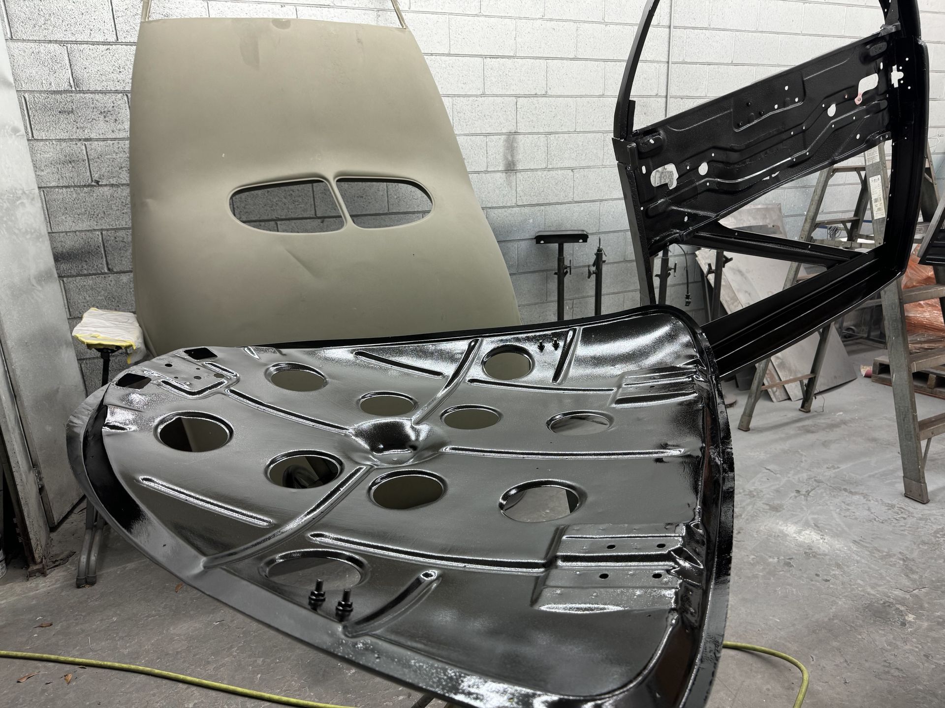 A piece of metal with holes in it is sitting on the floor in a garage.